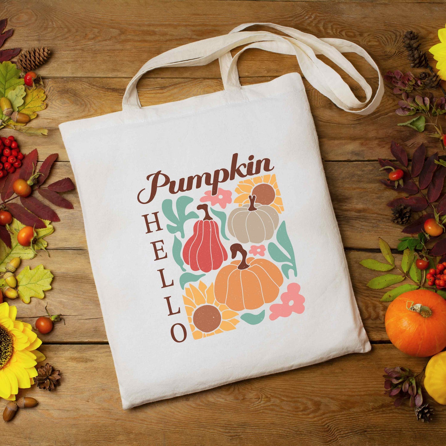 Canvas tote bag flat lay, printed with pumpkins, sunflowers, and the phrase “Hello Pumpkin” in fall-themed colors.