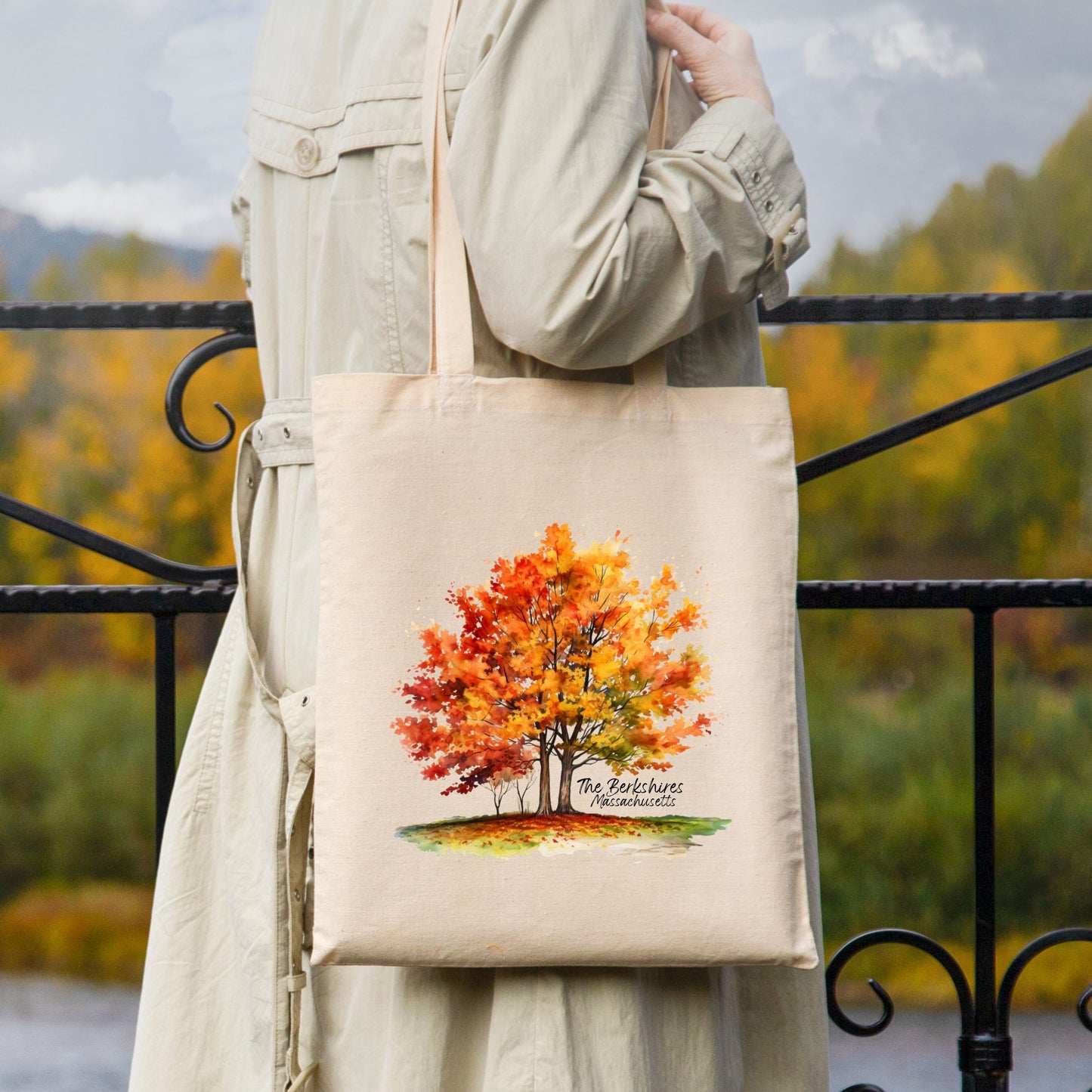 Woman carrying a natural cotton tote bag outdoors with a printed watercolor maple tree in fall colors and the text “The Berkshires Massachusetts”