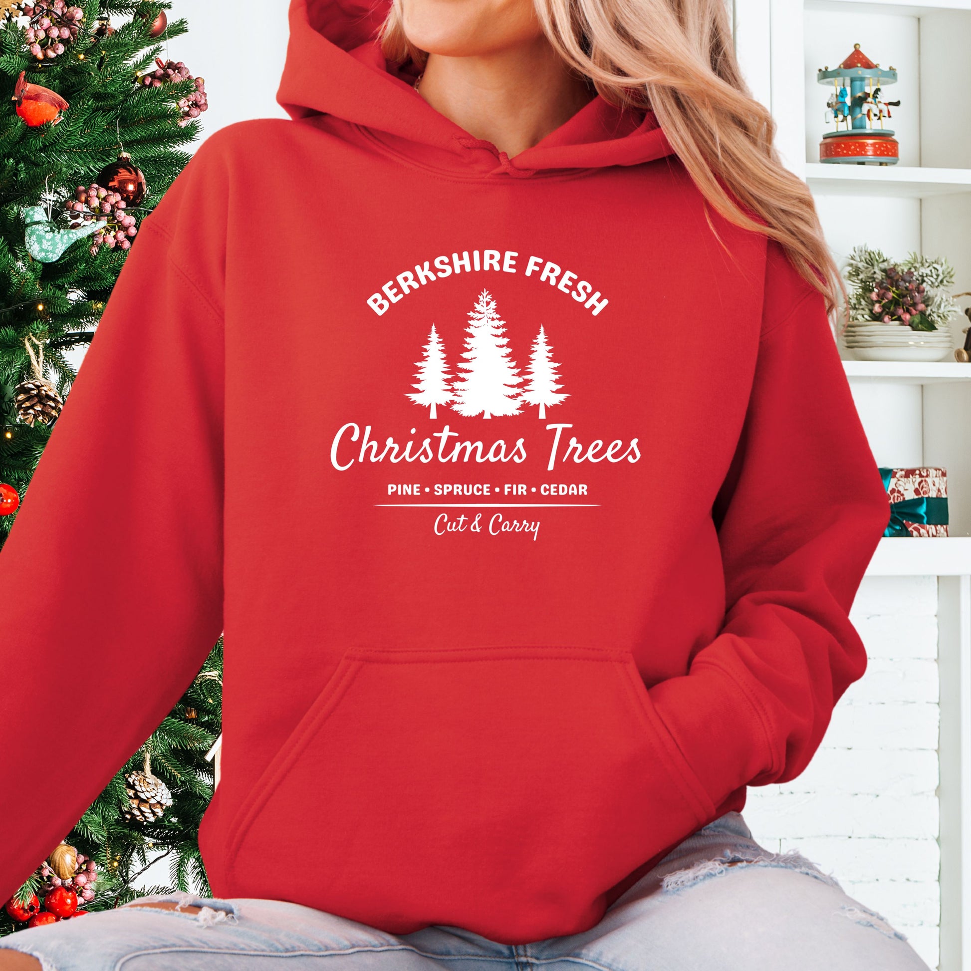 Model wearing red Berkshire Fresh Christmas Trees hoodie with holiday tree farm graphic on the front