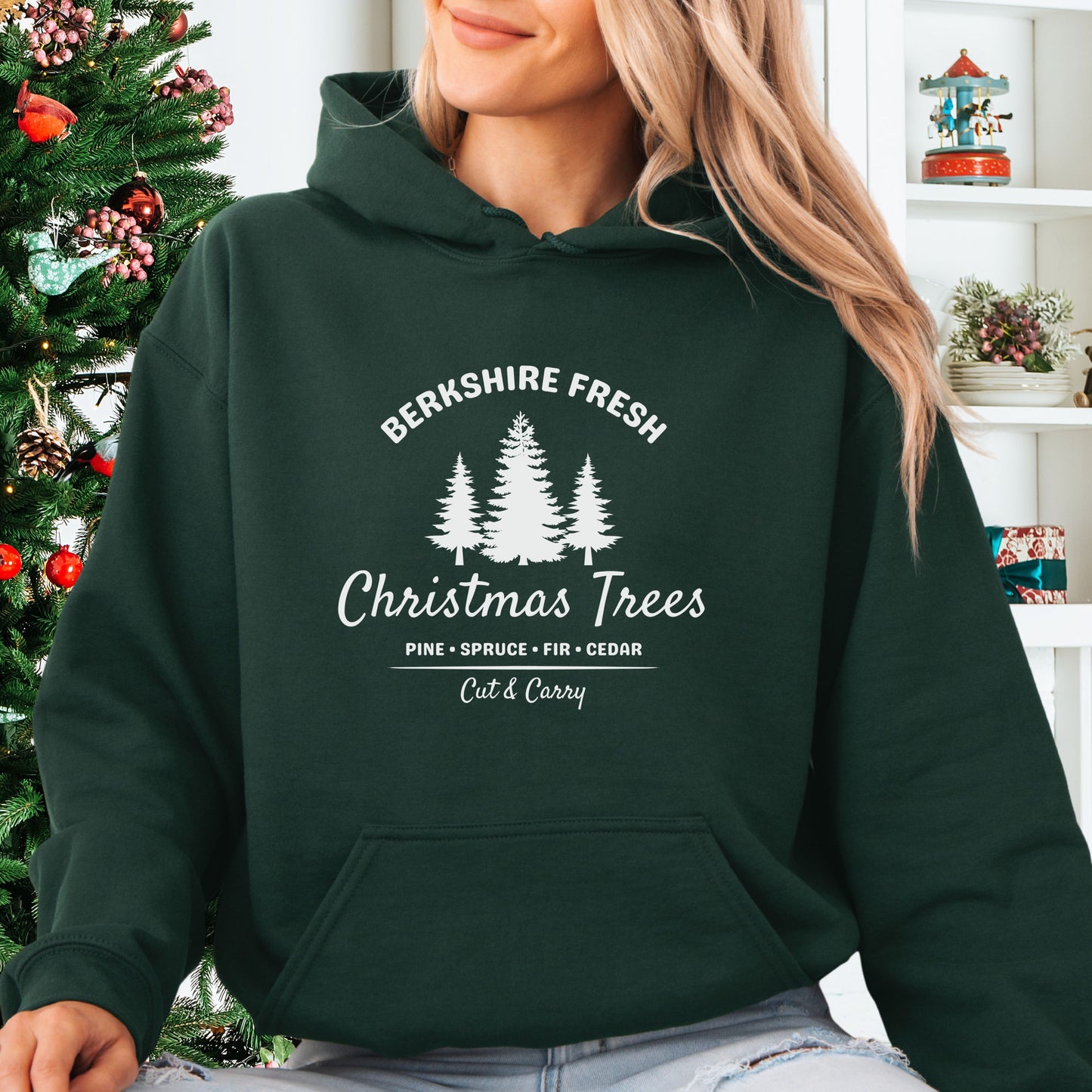 Model wearing forest green Berkshire Fresh Christmas Trees hoodie with holiday tree farm graphic on the front
