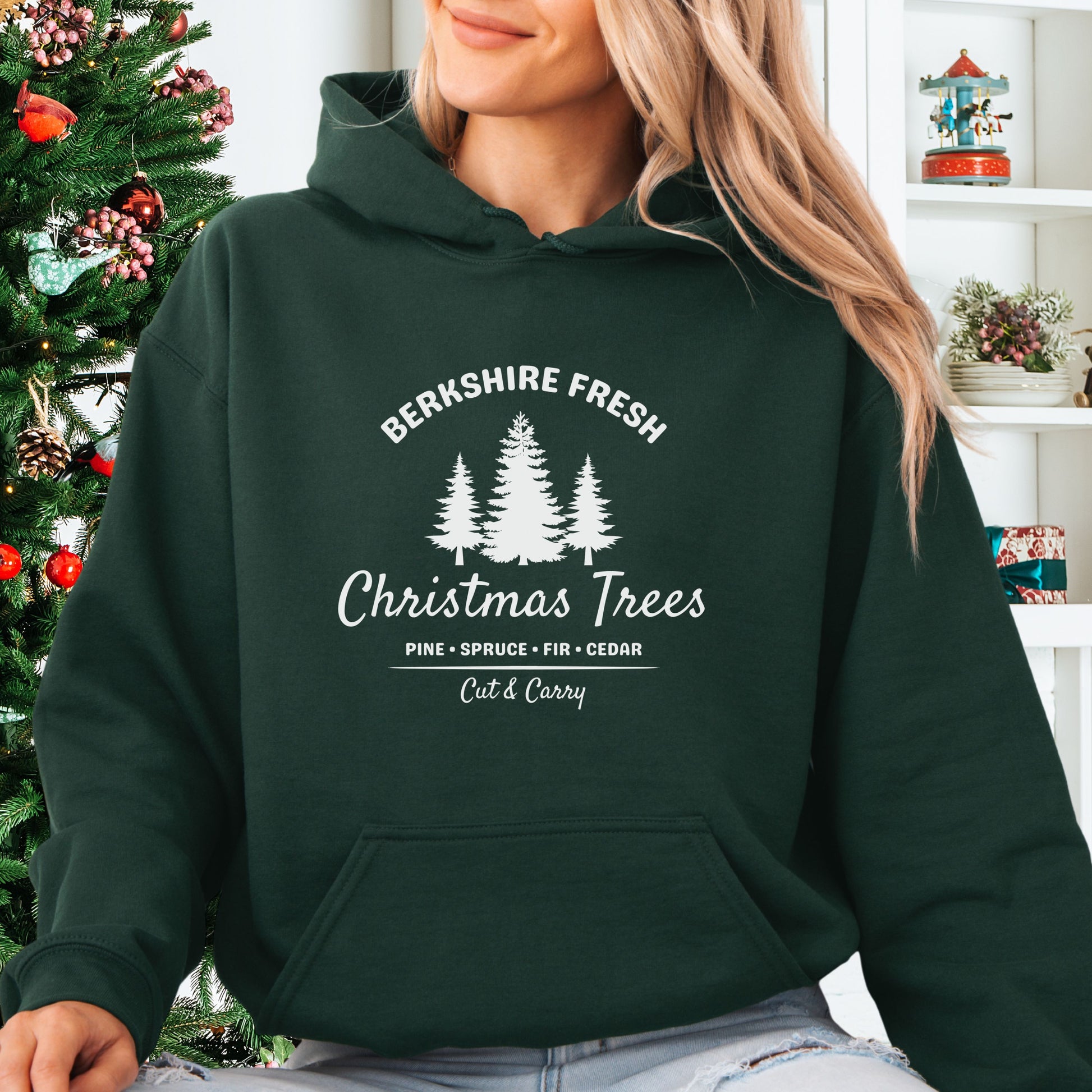 Model wearing forest green Berkshire Fresh Christmas Trees hoodie with holiday tree farm graphic on the front