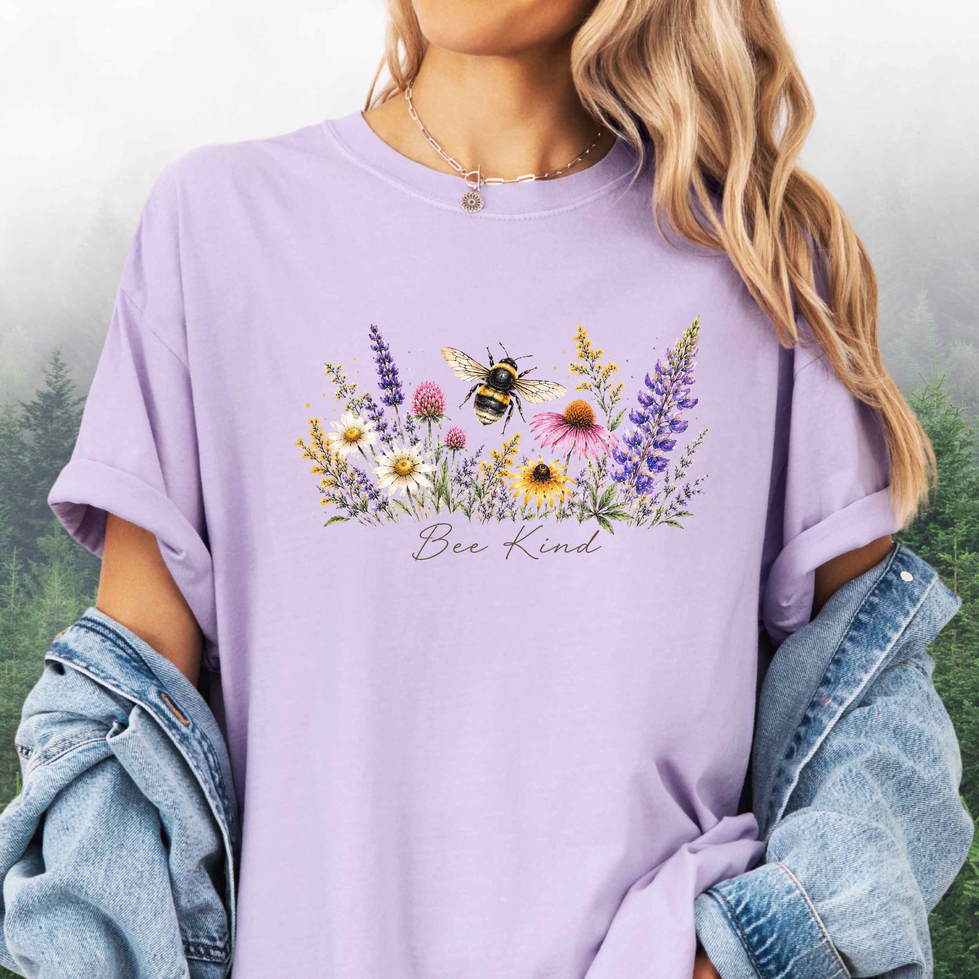 Person wearing Bee Kind Comfort Colors t-shirt with watercolor bee and wildflowers in the color orchard.