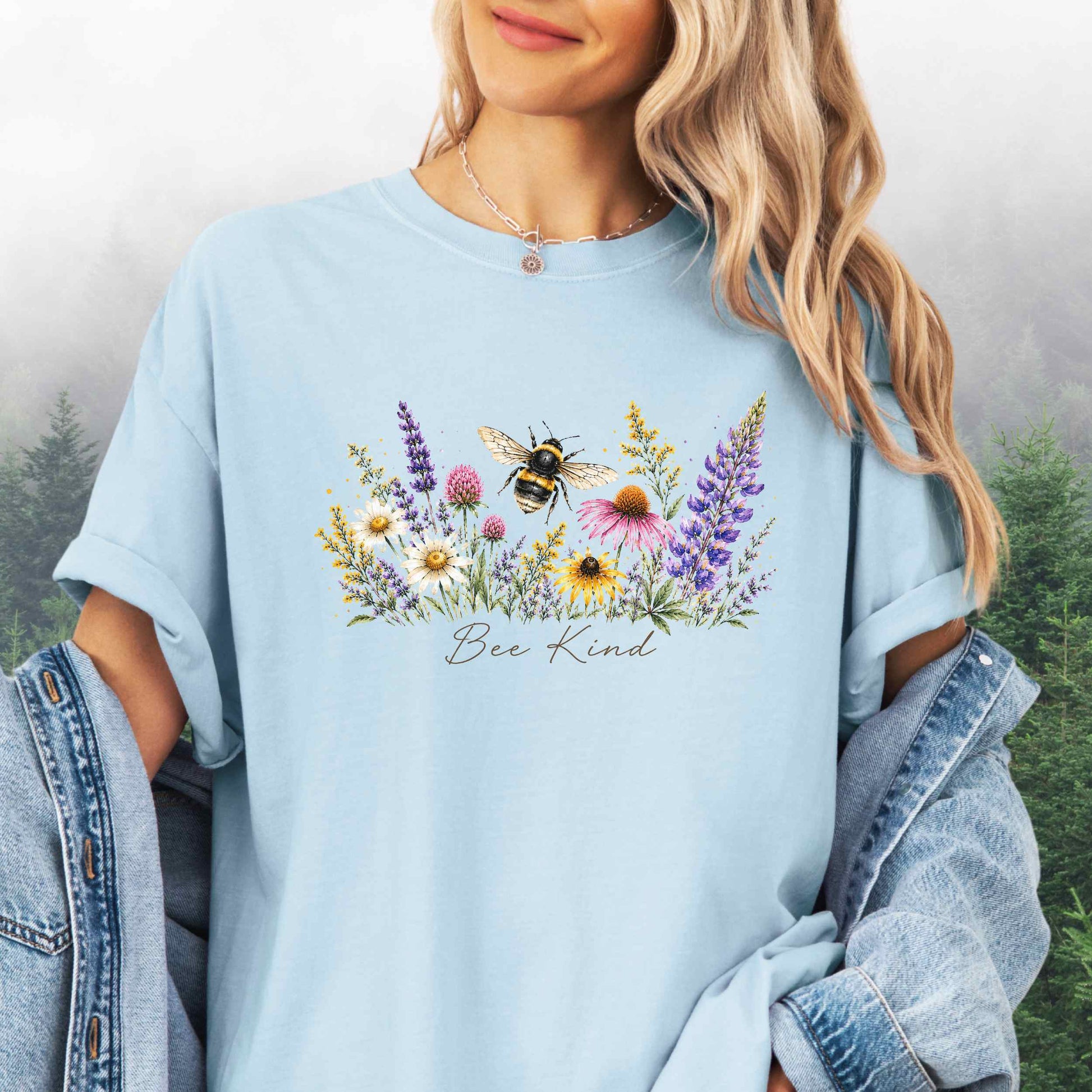 Person wearing Bee Kind Comfort Colors t-shirt with watercolor bee and wildflowers in the color chambray.