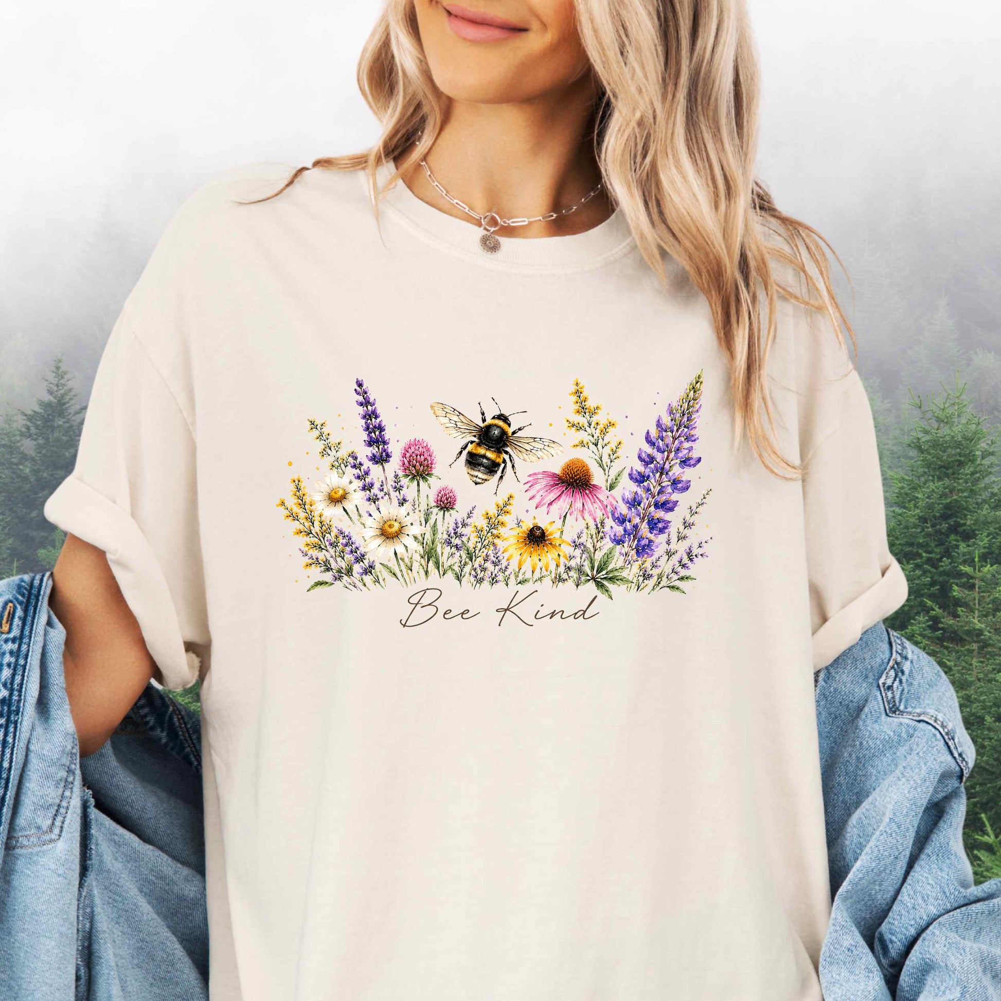 Person wearing Bee Kind Comfort Colors t-shirt with watercolor bee and wildflowers in the color ivory.
