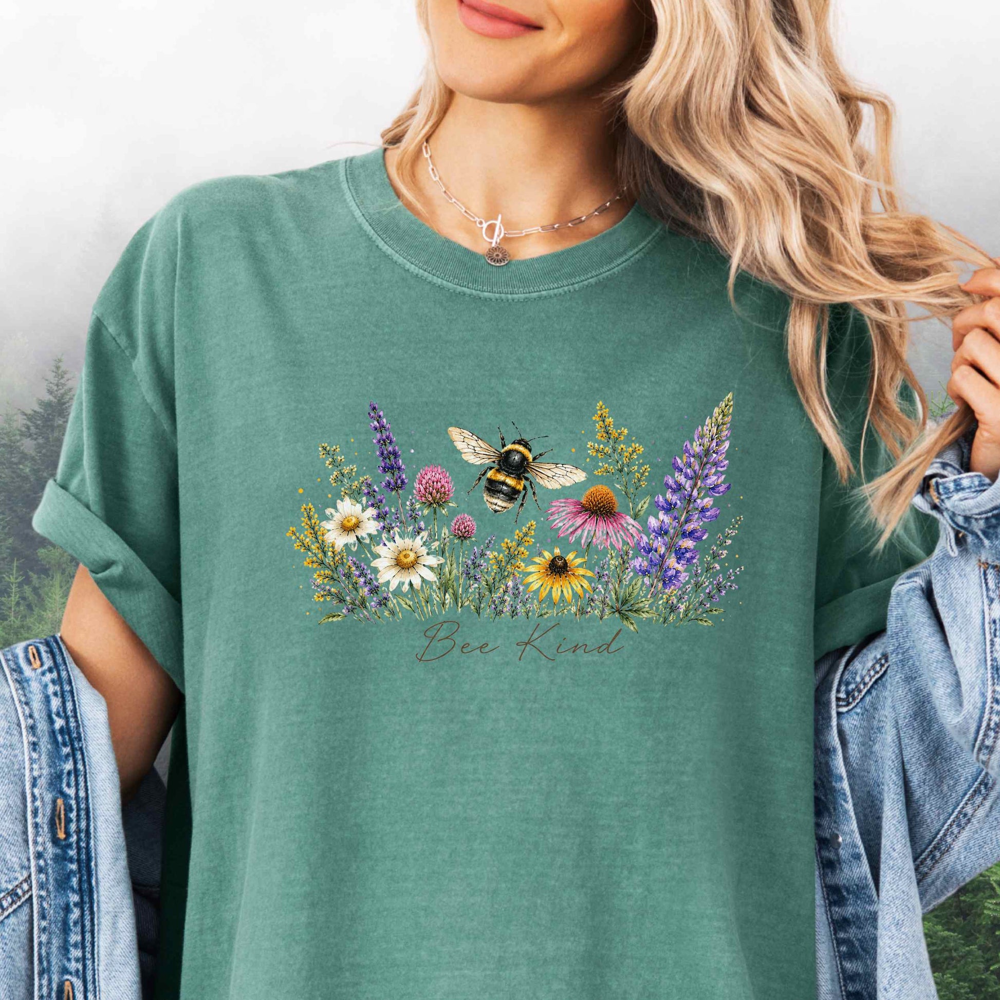 Person wearing Bee Kind Comfort Colors t-shirt with watercolor bee and wildflowers in the color light green.