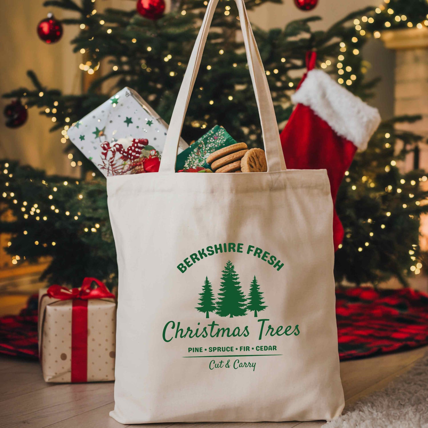 Tote bag with 'Berkshire Fresh Christmas Trees' design in front of a Christmas tree and presents.