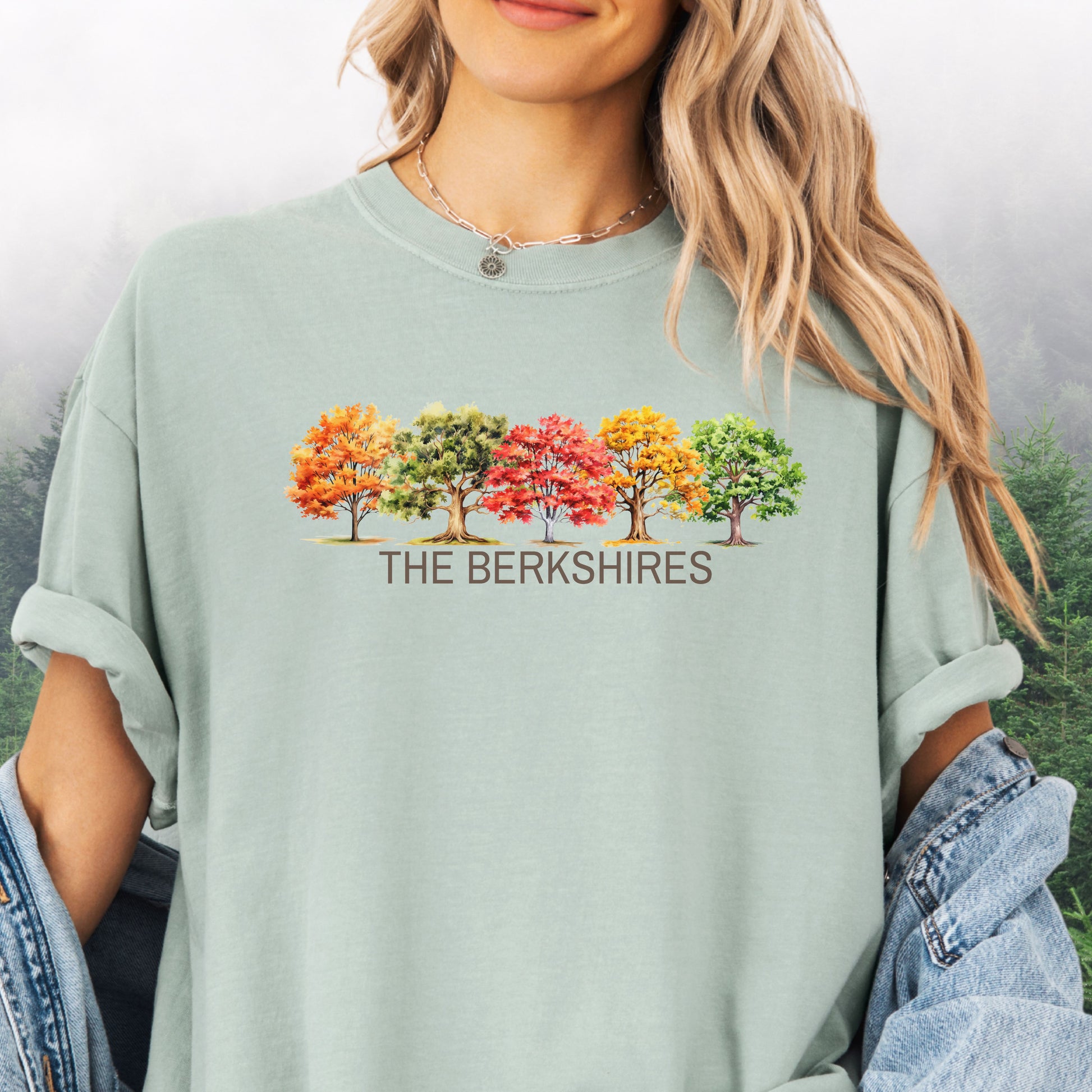 Person wearing The Berkshires Fall Comfort Colors t-shirt with autumn trees design in the color bay.