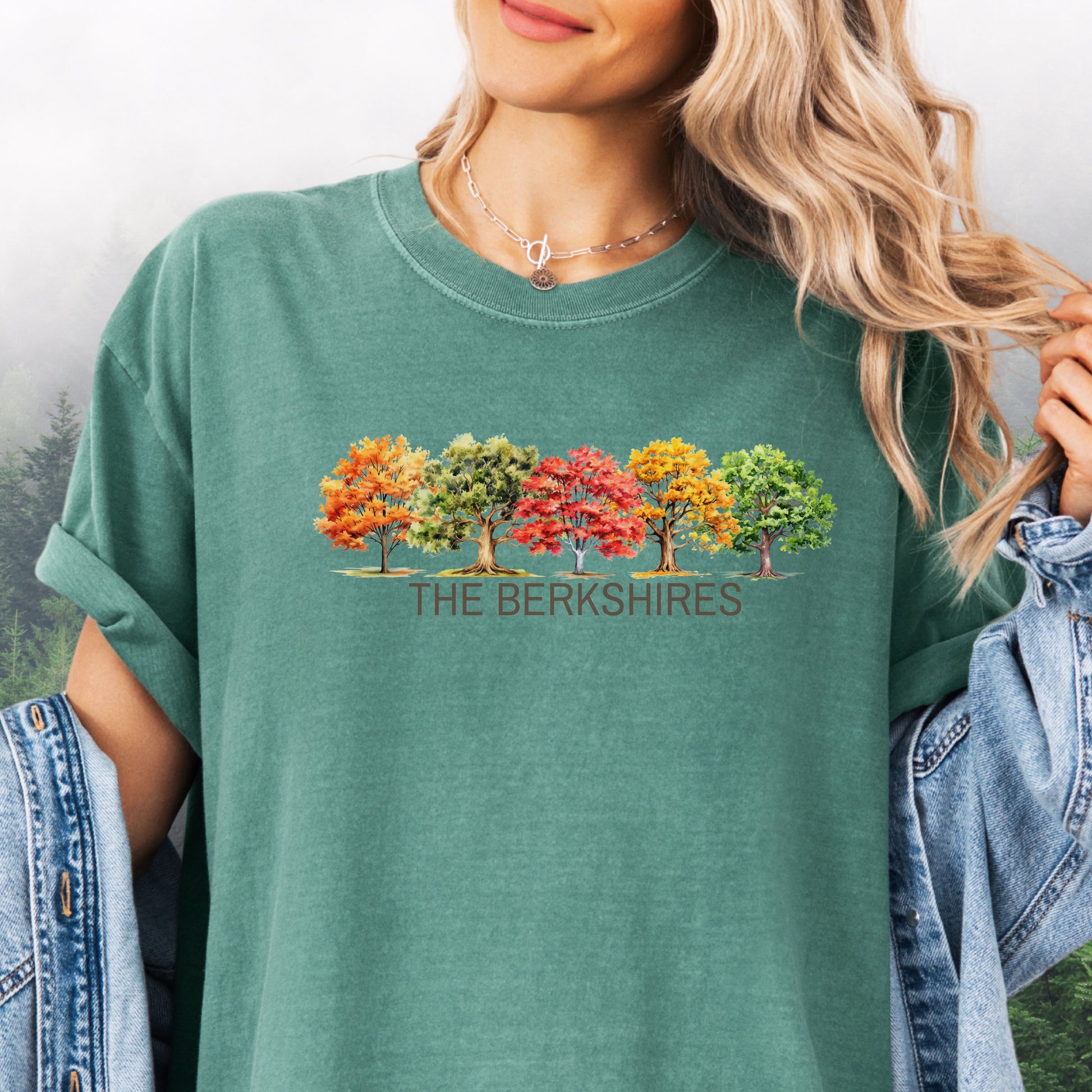 Person wearing The Berkshires Fall Comfort Colors t-shirt with autumn trees design in the color light green.