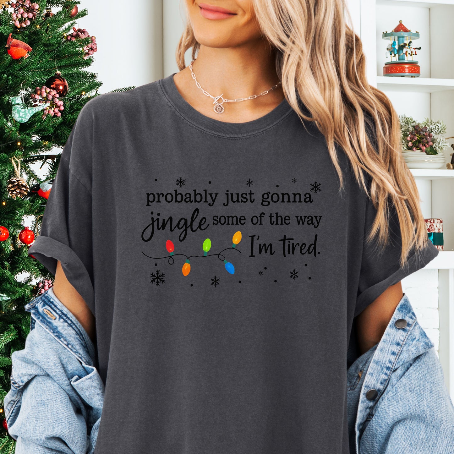 Person wearing pepper comfort colors shirt with colorful Christmas lights and funny text that says probably just gonna jingle some of the way I’m tired