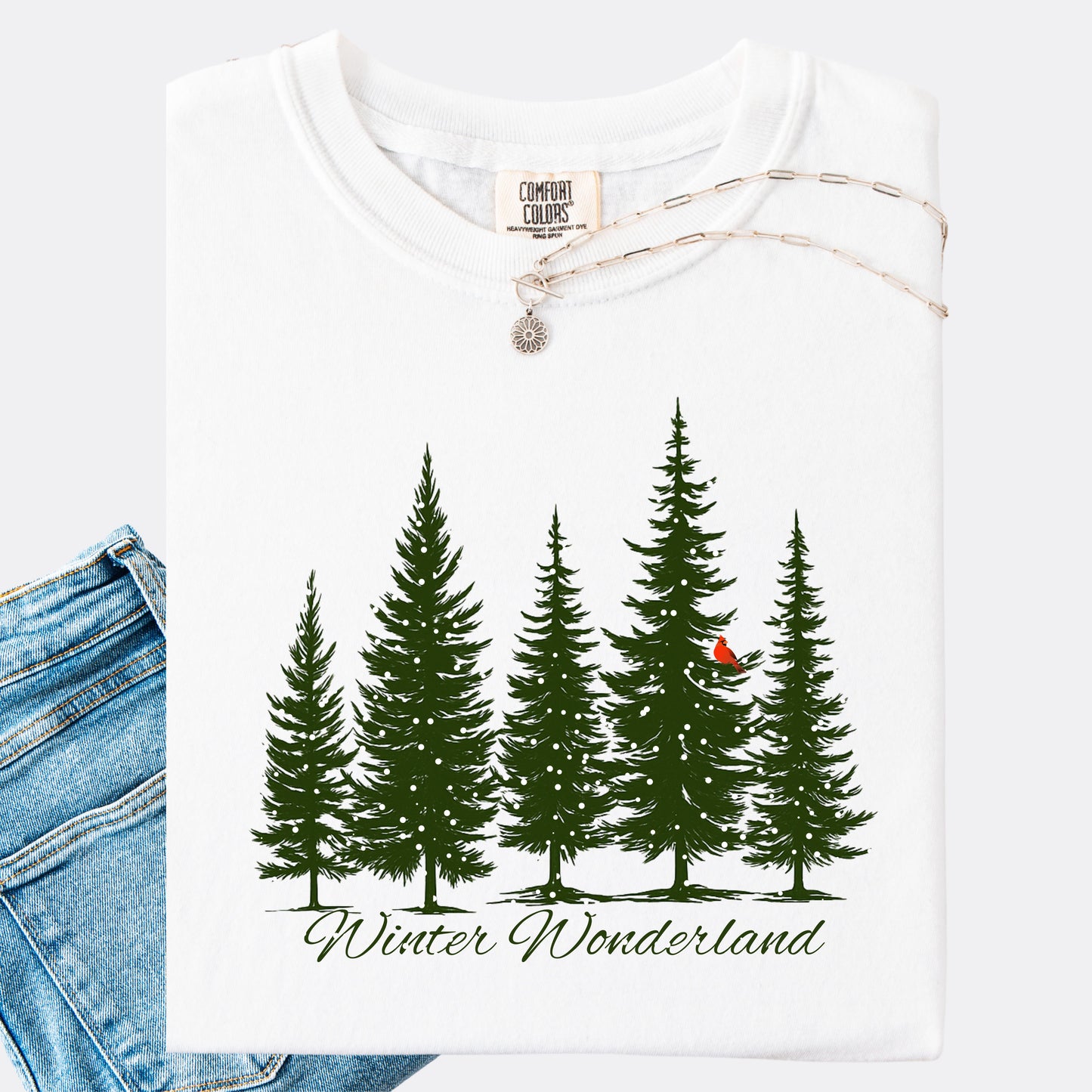 Snowy pine tree and red cardinal design on white cotton comfort colors t-shirt with the text Winter Wonderland
