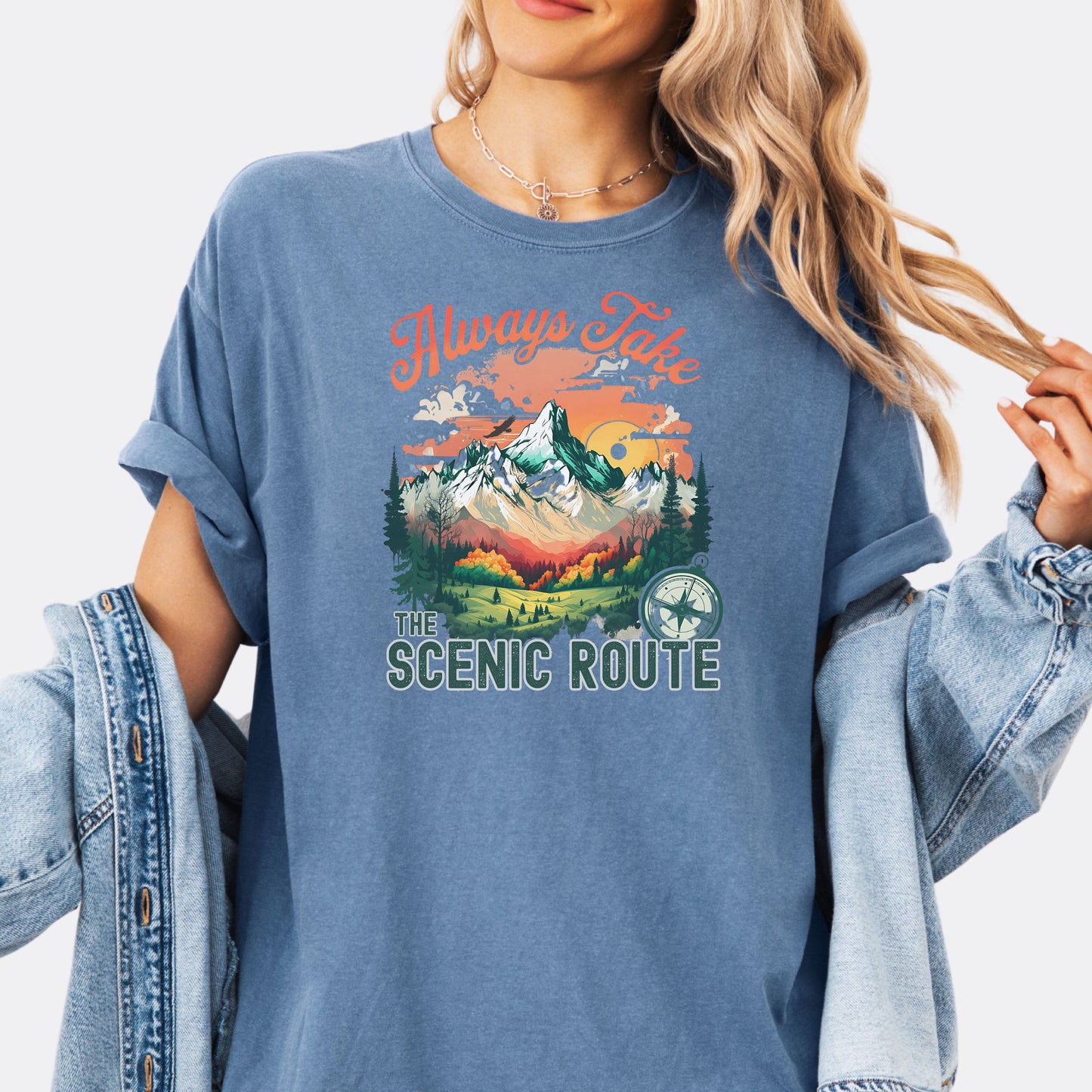 Person wearing a Comfort Colors T-shirt  in the color Blue Jean with a nature-inspired “Always Take the Scenic Route” design on the front.