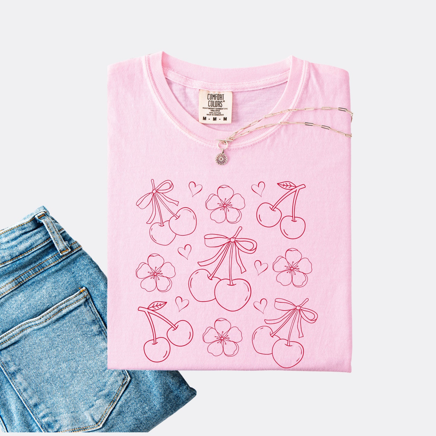Comfort Colors shirt in the color blossom with graphic of cherries, cherry blossoms and hearts, red ink.