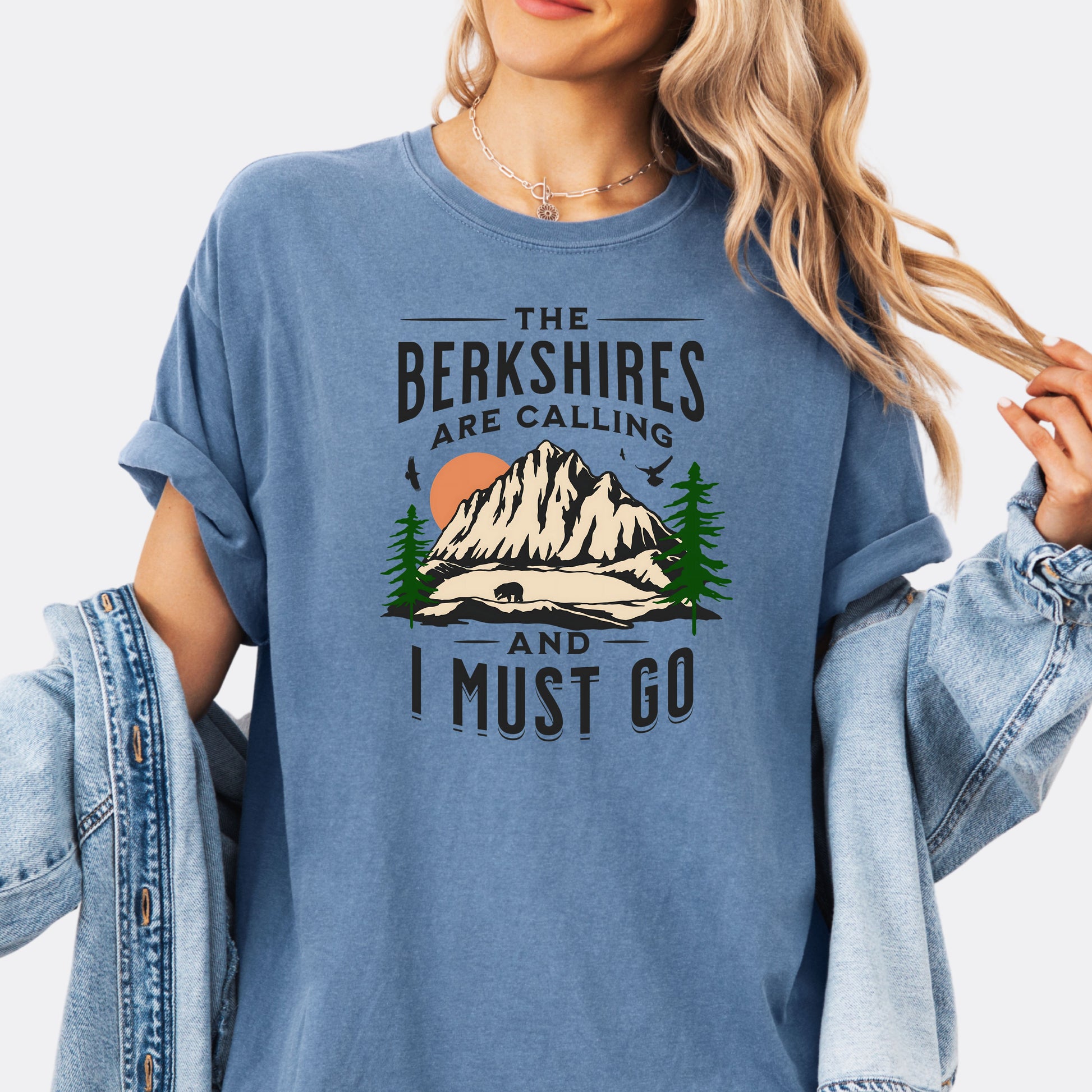 Person wearing Comfort Colors 1717 T-shirt in blue jean. Shirt features a graphic design of mountains, pine trees, and a bear with the text ‘The Berkshires are calling and I must go.’”