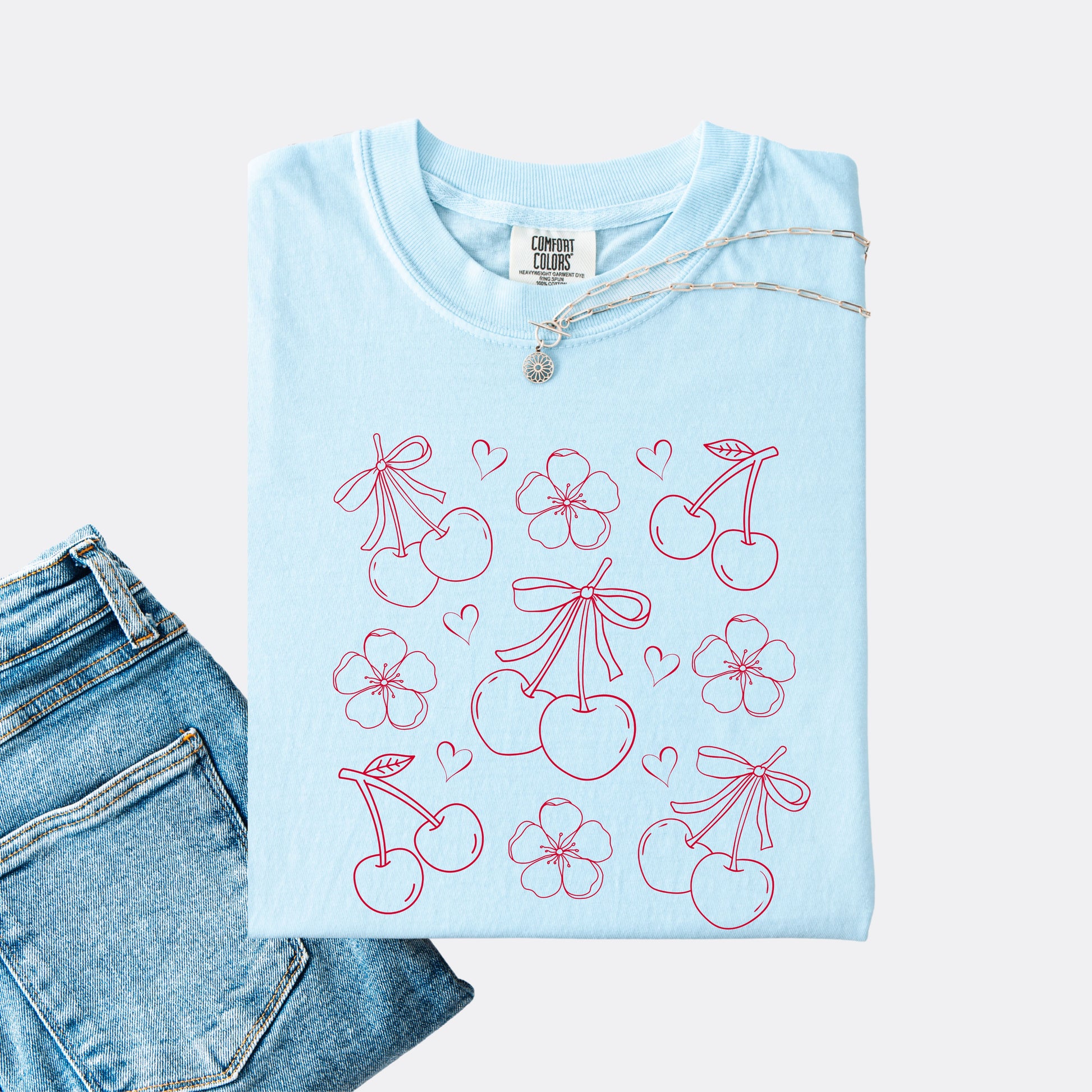 Comfort Colors shirt in the color chambray with graphic of cherries, cherry blossoms and hearts, red ink.