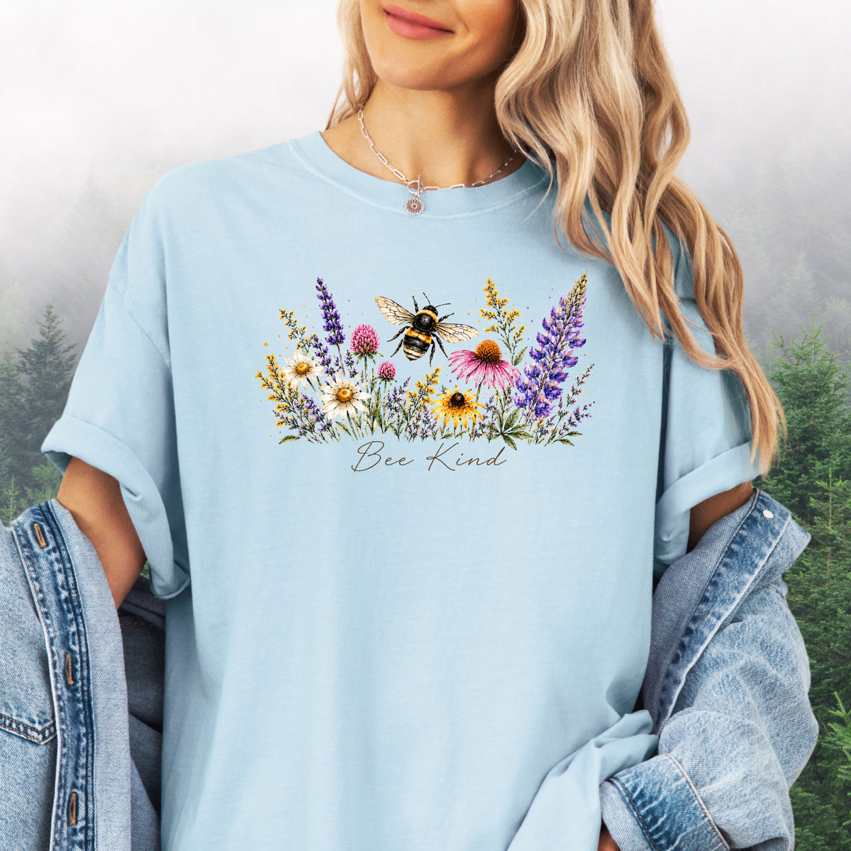 Person wearing Bee Kind Comfort Colors t-shirt with watercolor bee and wildflowers in the color chambray.