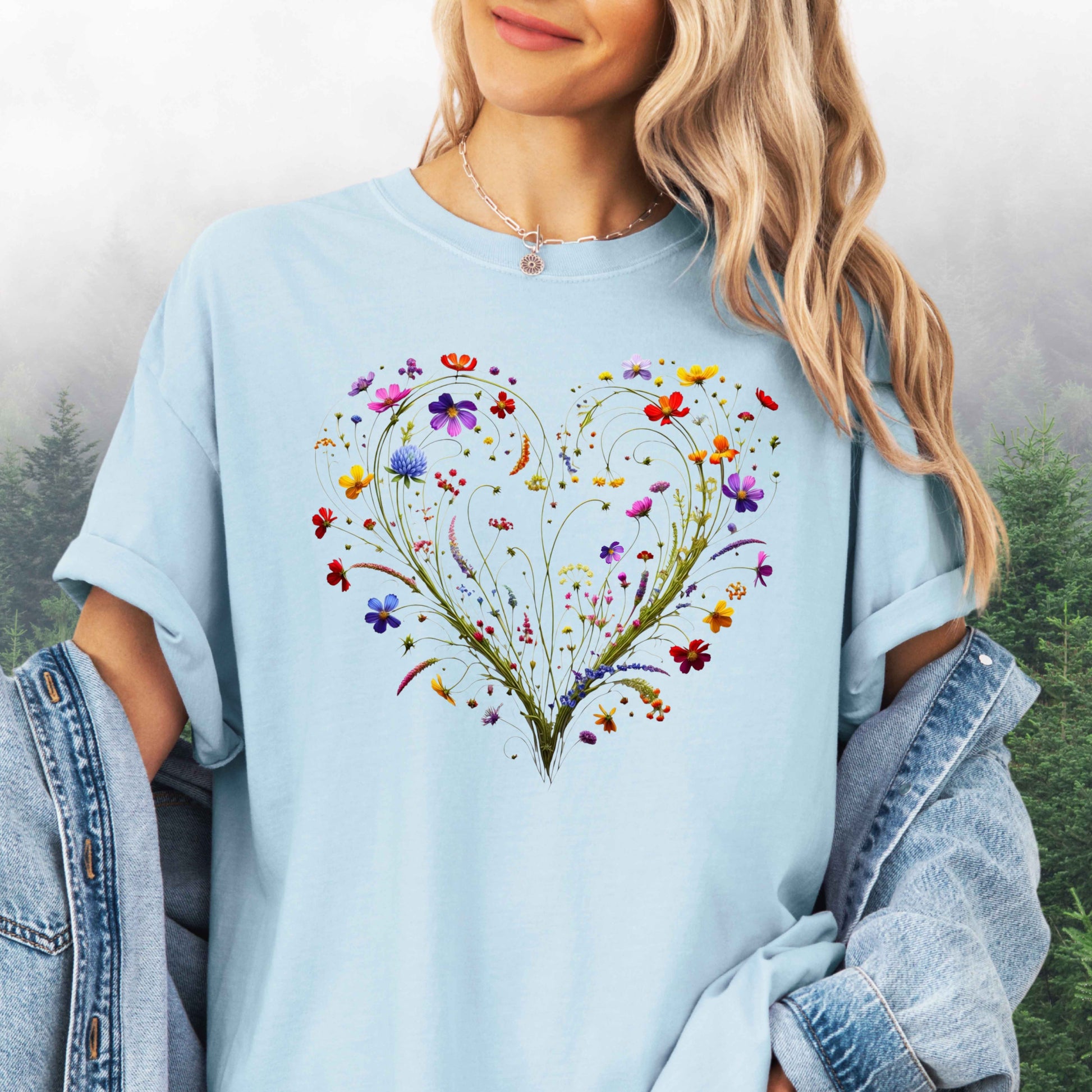 Person wearing a chambray colored shirt with a wildflower heart graphic