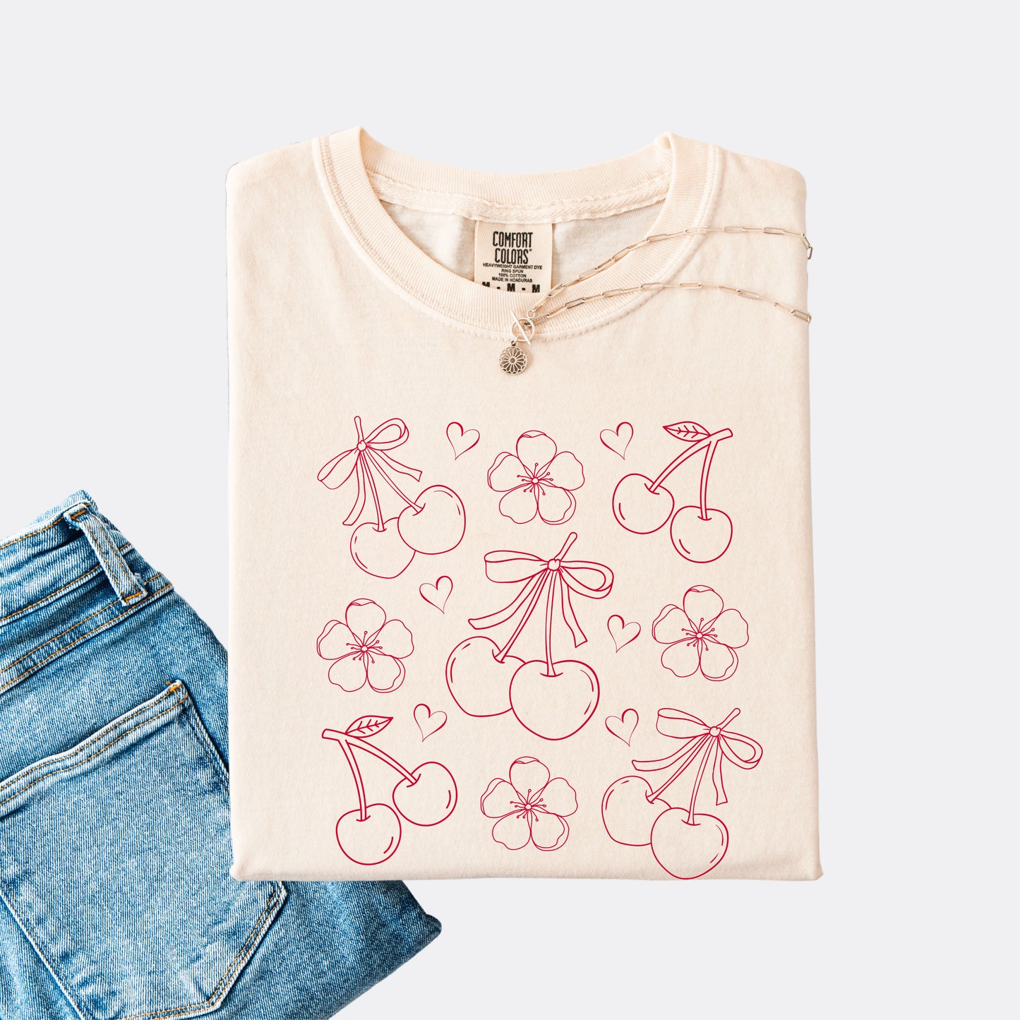 Comfort Colors shirt in ivory with graphic of cherries, cherry blossoms and hearts, red ink.