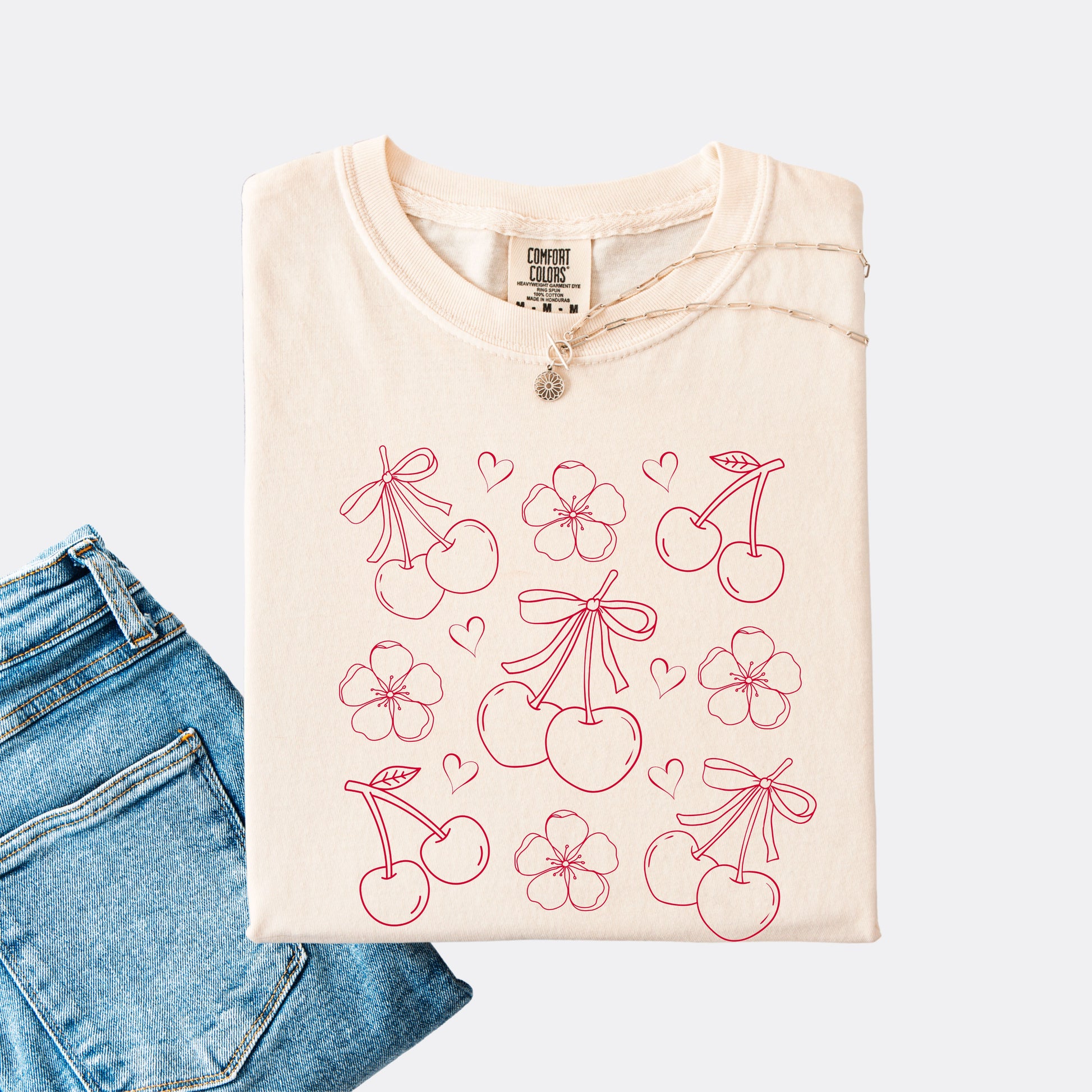 Comfort Colors shirt in ivory with graphic of cherries, cherry blossoms and hearts, red ink.