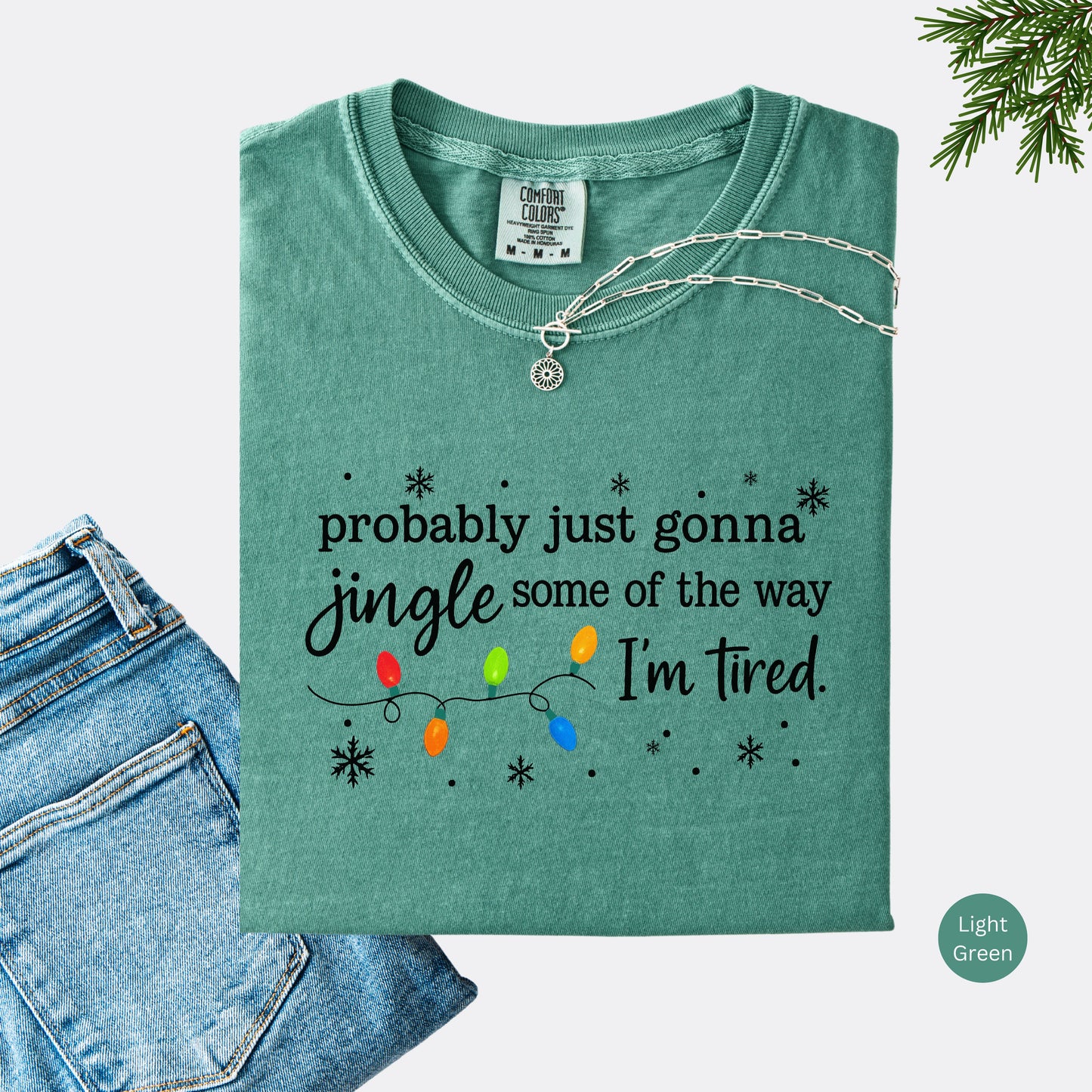 Light green comfort colors shirt with colorful Christmas lights and funny text that says probably just gonna jingle some of the way I’m tired