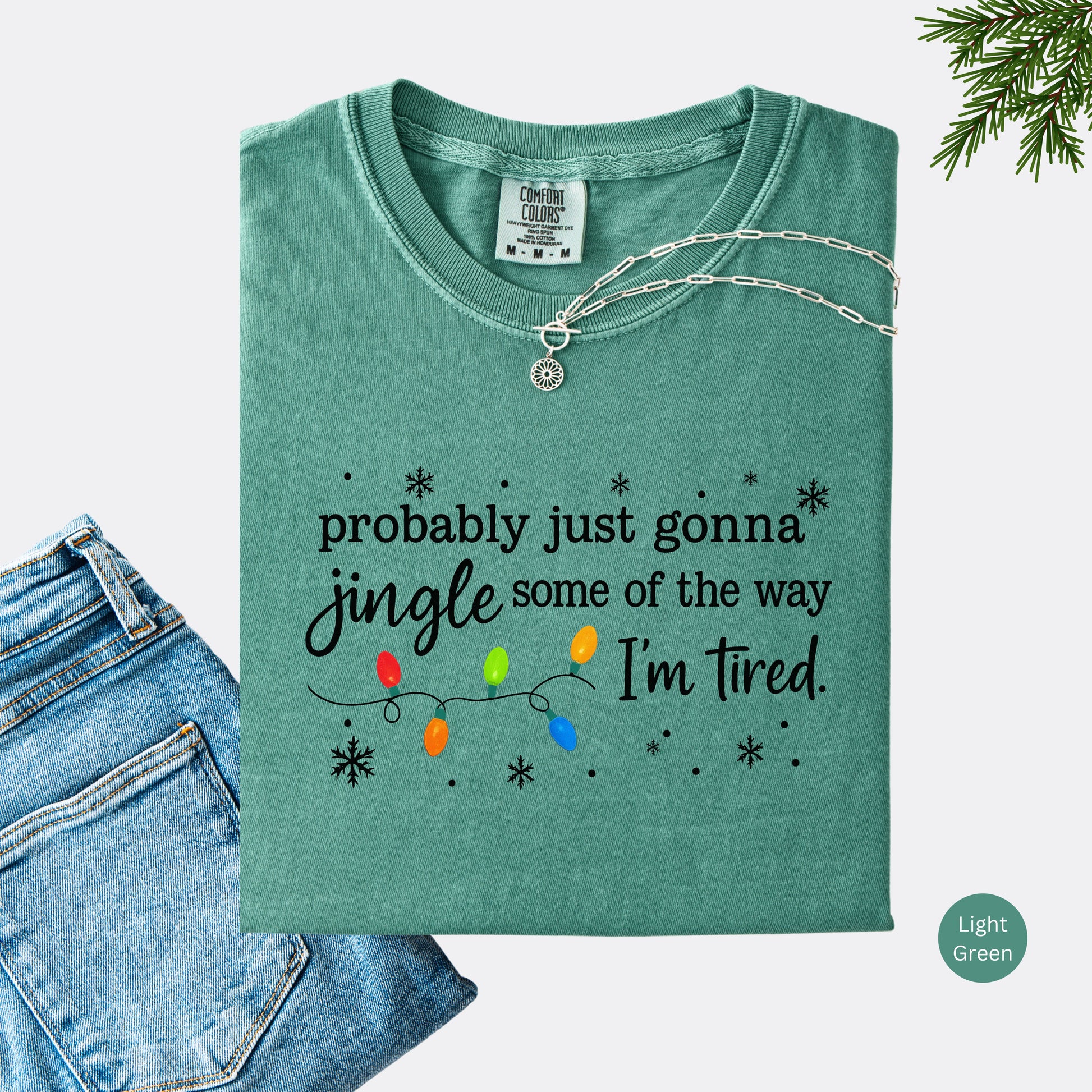 Light green comfort colors shirt with colorful Christmas lights and funny text that says probably just gonna jingle some of the way I’m tired