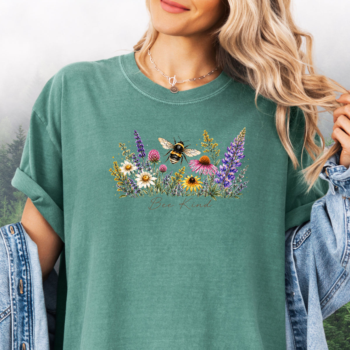Person wearing Bee Kind Comfort Colors t-shirt with watercolor bee and wildflowers in the color light green.