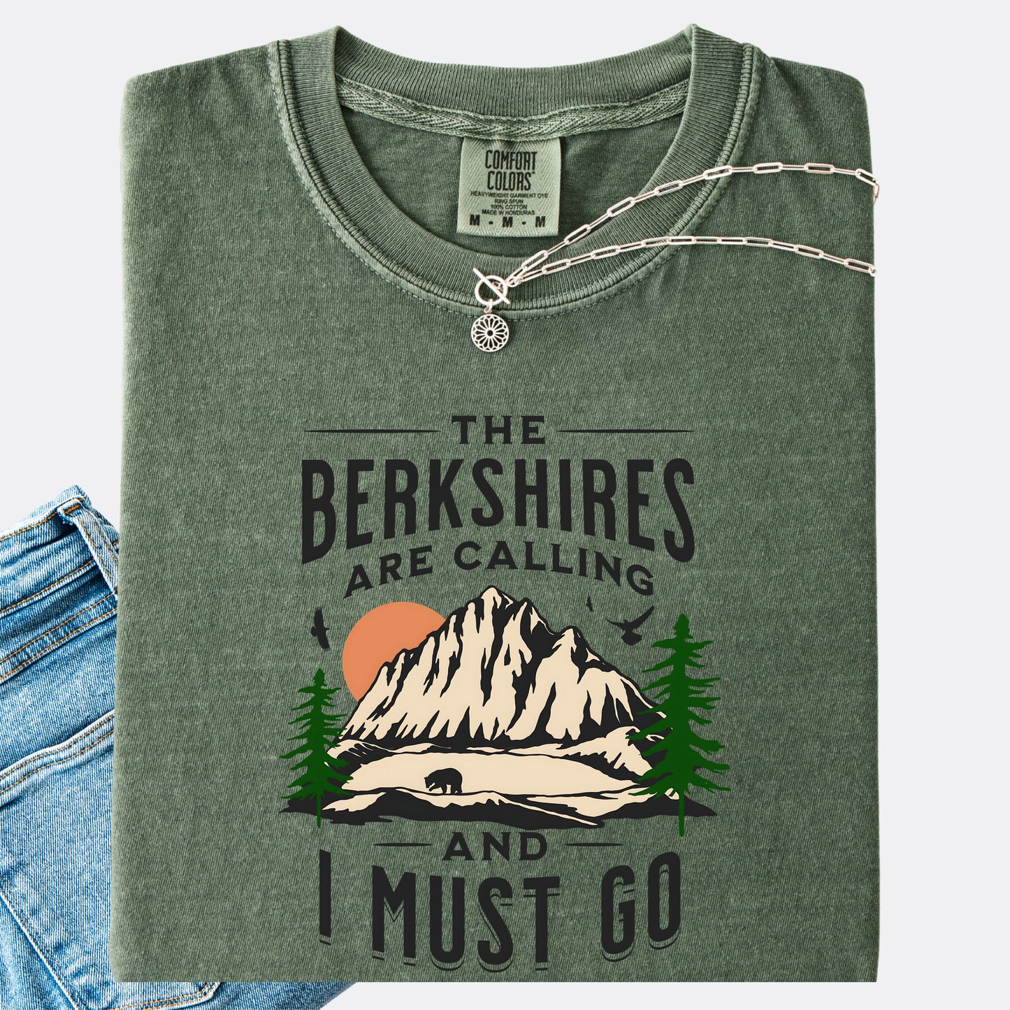 Comfort Colors 1717 T-shirt in moss. Shirt features a graphic design of mountains, pine trees, and a bear with the text ‘The Berkshires are calling and I must go.’”