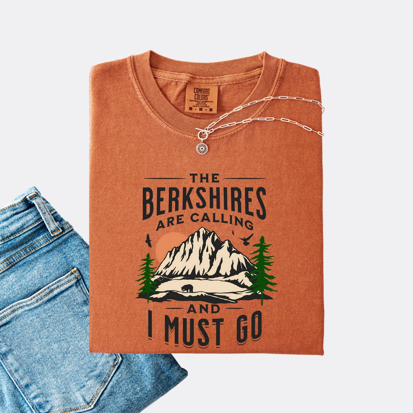 Comfort Colors 1717 T-shirt in the color yam. Shirt features a graphic design of mountains, pine trees, and a bear with the text ‘The Berkshires are calling and I must go.’”