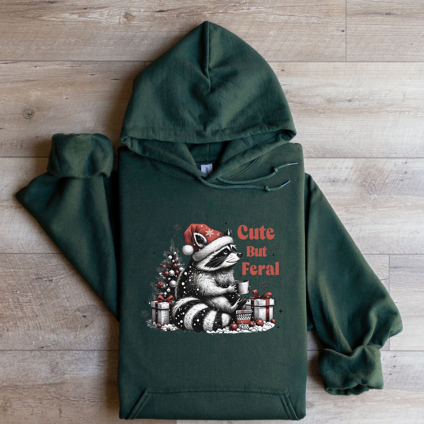 Cute But Feral Hooded Sweatshirt with racoon flat lay spruce green color