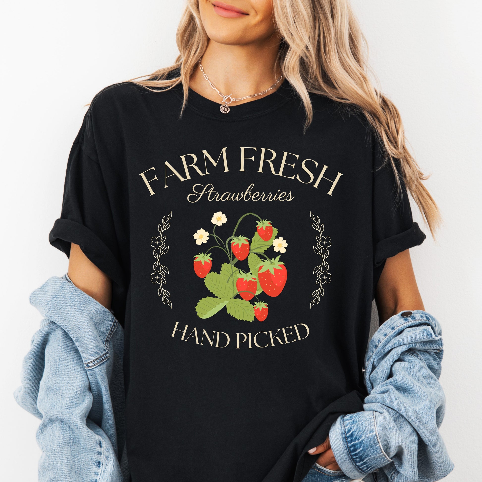 Person wearing a black t-shirt with 'Farm Fresh Strawberries Hand Picked' design.