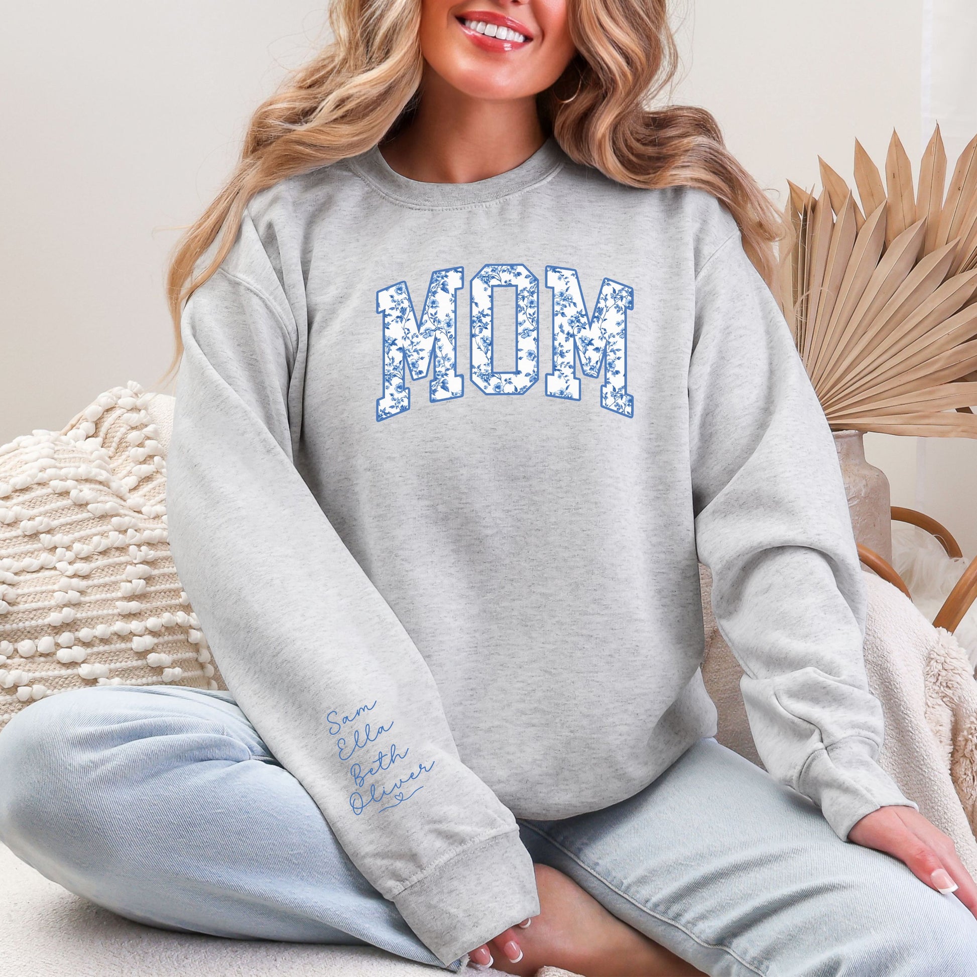 Woman wearing floral MOM crewneck sweatshirt featuring personalized kids names printed on the sleeve, ash