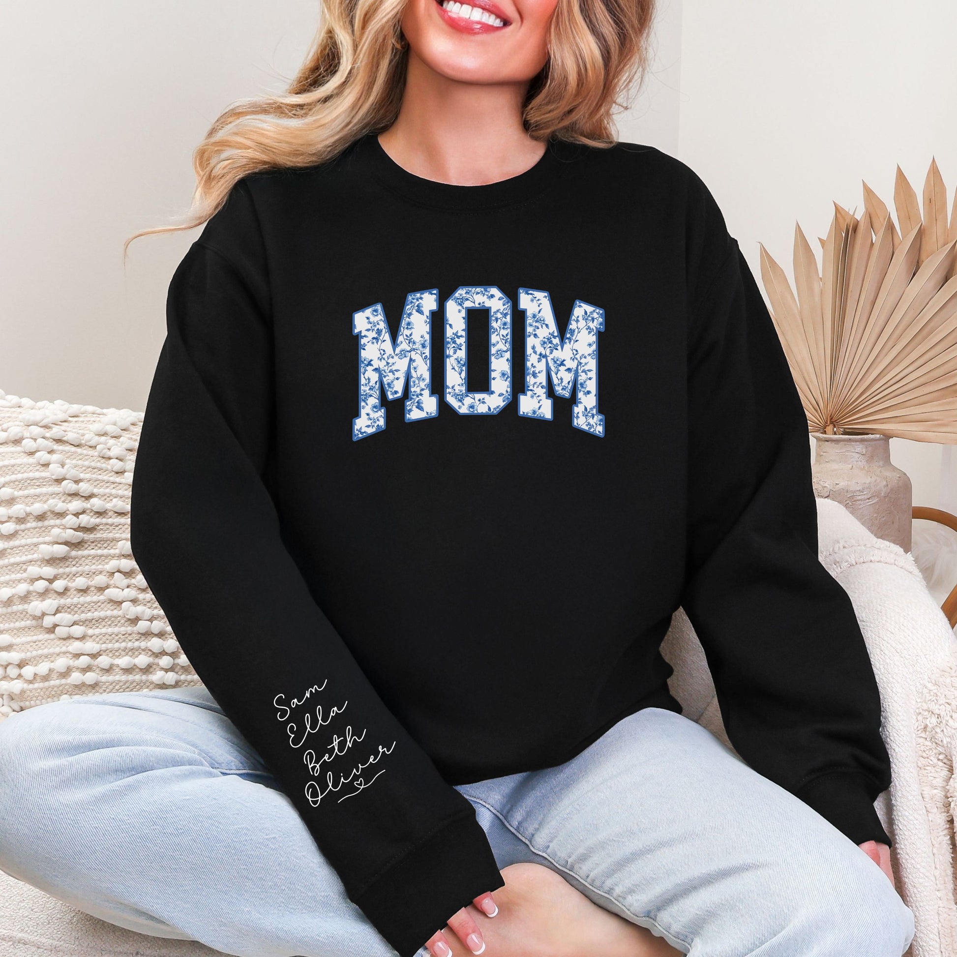 Woman wearing floral MOM crewneck sweatshirt featuring personalized kids names printed on the sleeve, black