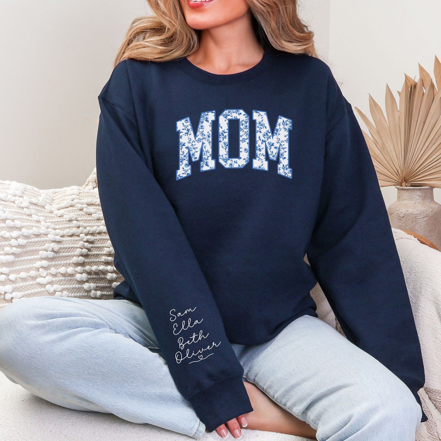 Woman wearing floral MOM crewneck sweatshirt featuring personalized kids names printed on the sleeve, navy