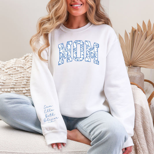Woman wearing floral MOM crewneck sweatshirt featuring personalized kids names printed on the sleeve, white