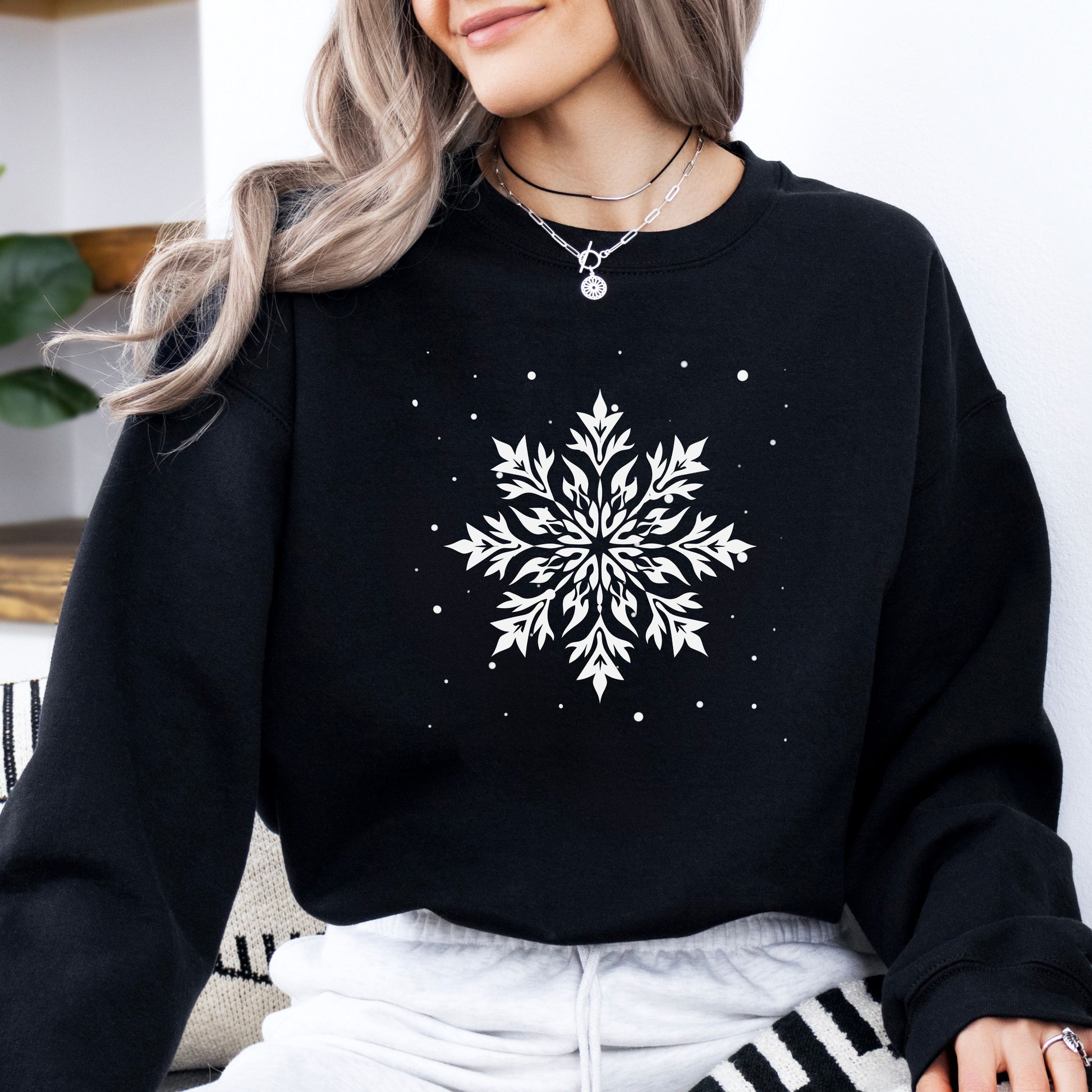 Person wearing snowflake design with falling snow on cozy unisex winter sweatshirt in the color black