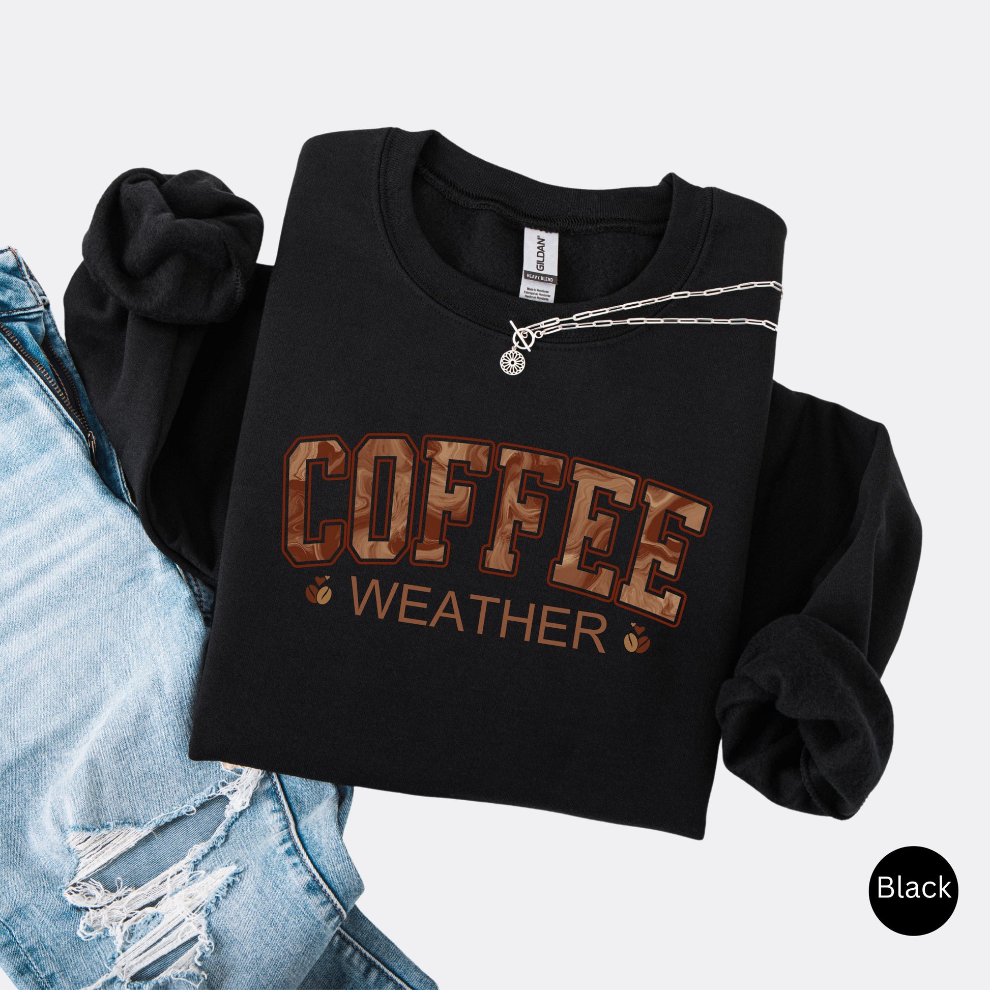 Coffee weather sweatshirt with marbled brown lettering and coffee bean icons on black crewneck.