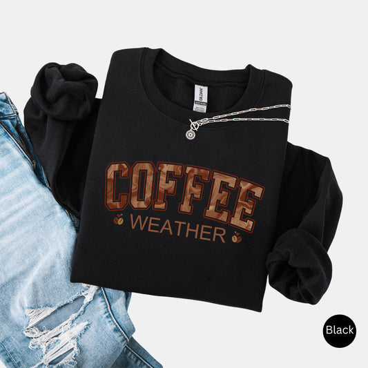 Coffee weather sweatshirt with marbled brown lettering and coffee bean icons on black crewneck.