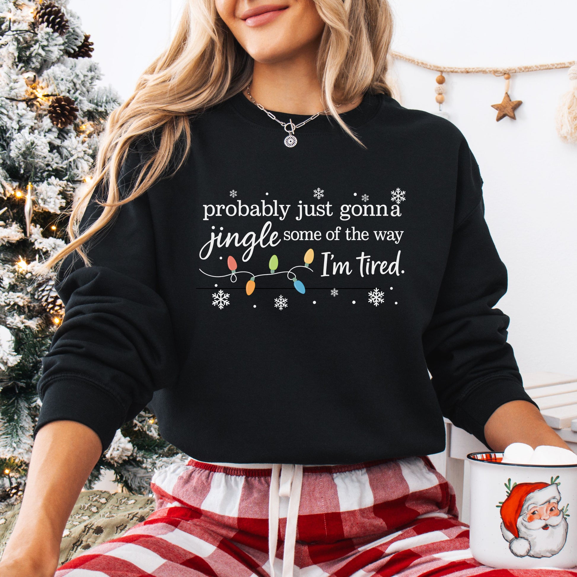 Person wearing a black sweatshirt with Christmas lights and the text "probably just gonna jingle some of the way I'm tired".