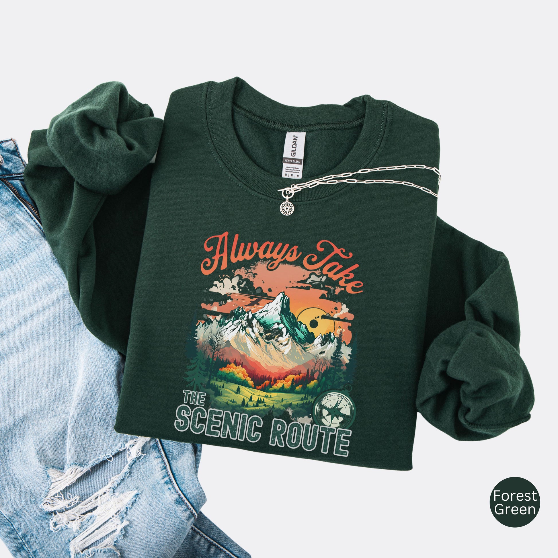 Crewneck sweatshirt in the color black with the phrase “Always Take the Scenic Route” and a mountain-inspired graphic on the front.