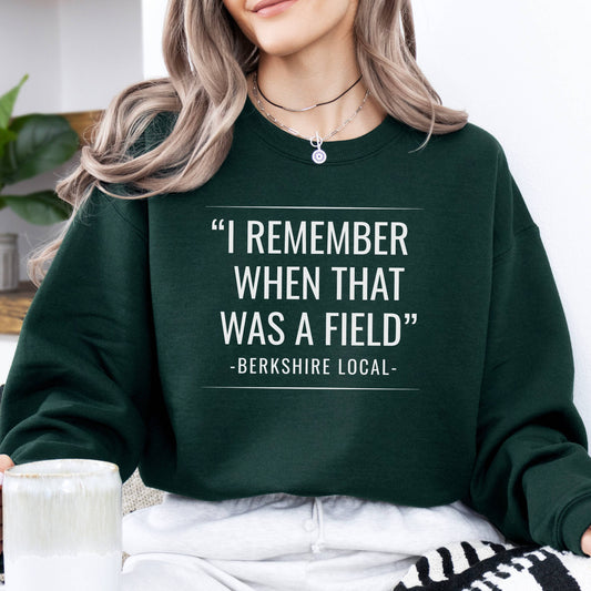 Person wearing sweatshirt with the quote "I remember when that was a field" -Berkshire Local-, in the color forest green