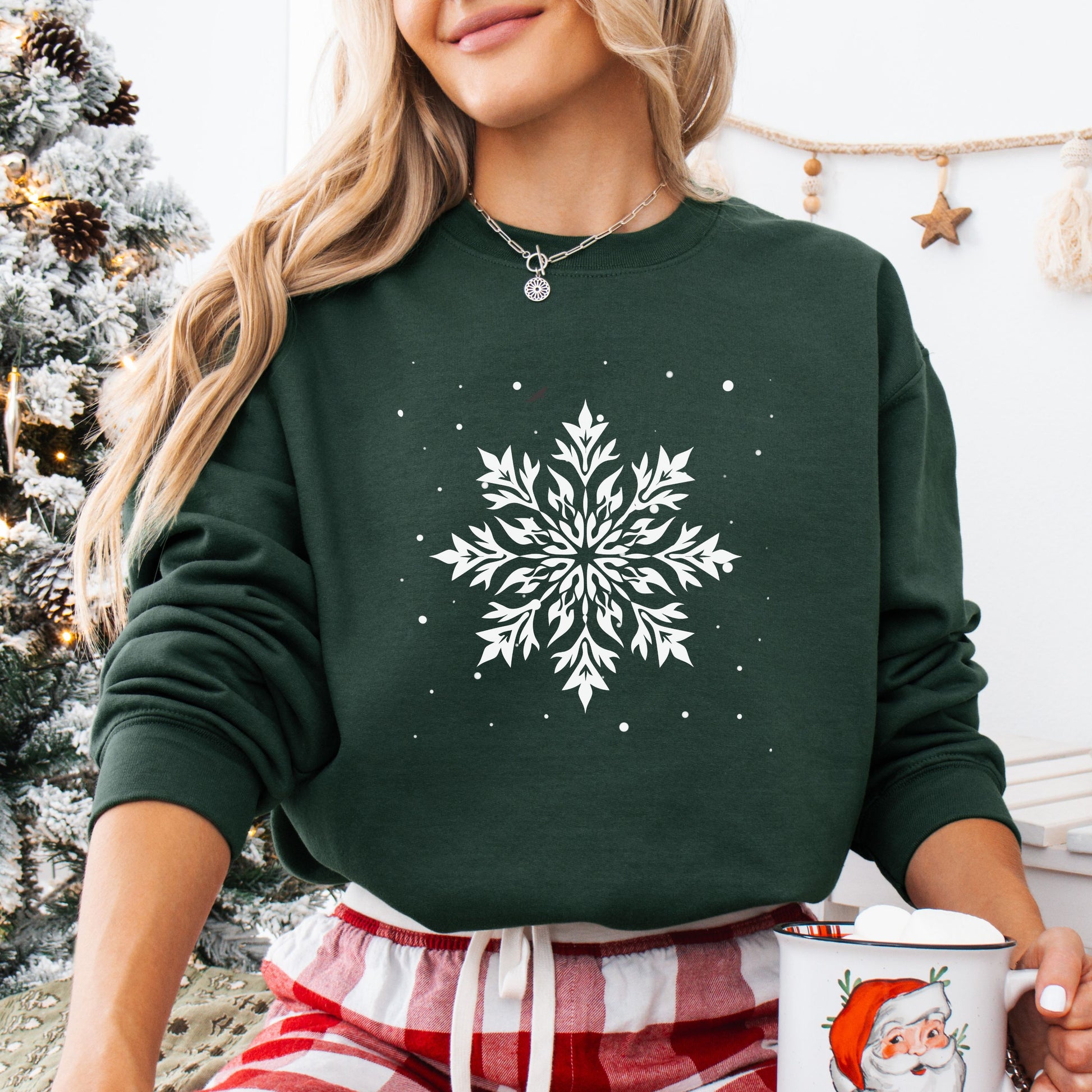 Person wearing snowflake design with falling snow on cozy unisex winter sweatshirt in the color forest green