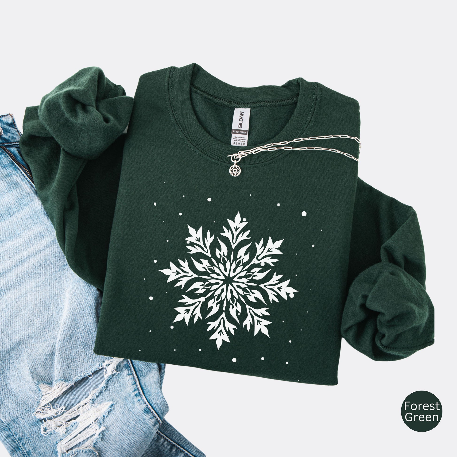 Snowflake design with falling snow on cozy unisex winter sweatshirt in the color forest green
