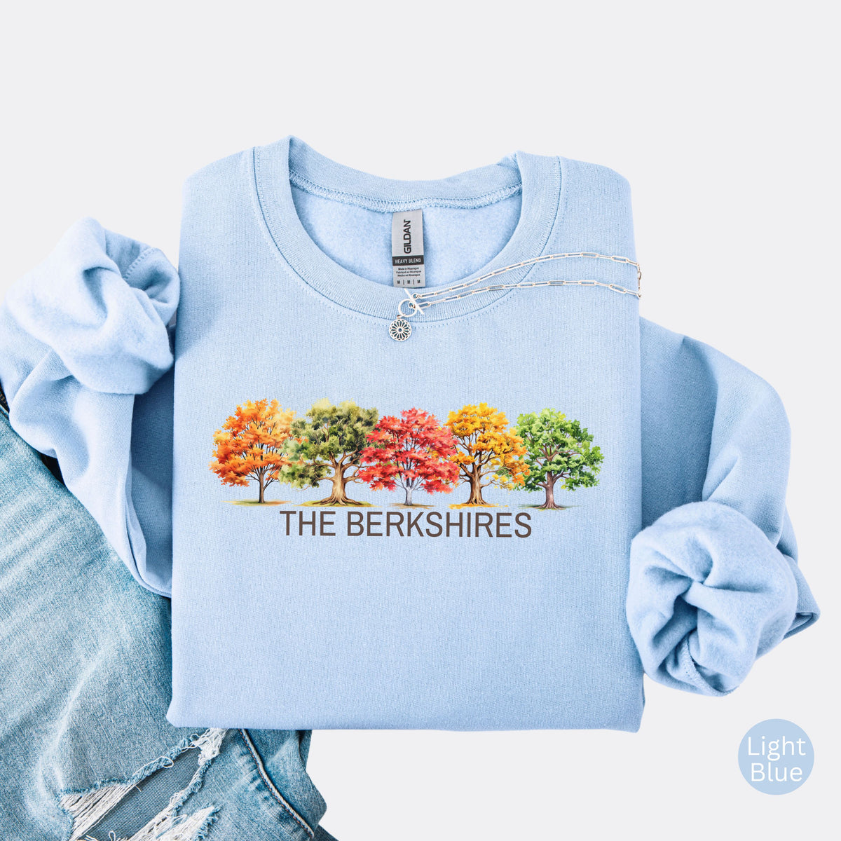 Light blue crewneck sweatshirt featuring colorful watercolor trees above the words The Berkshires.