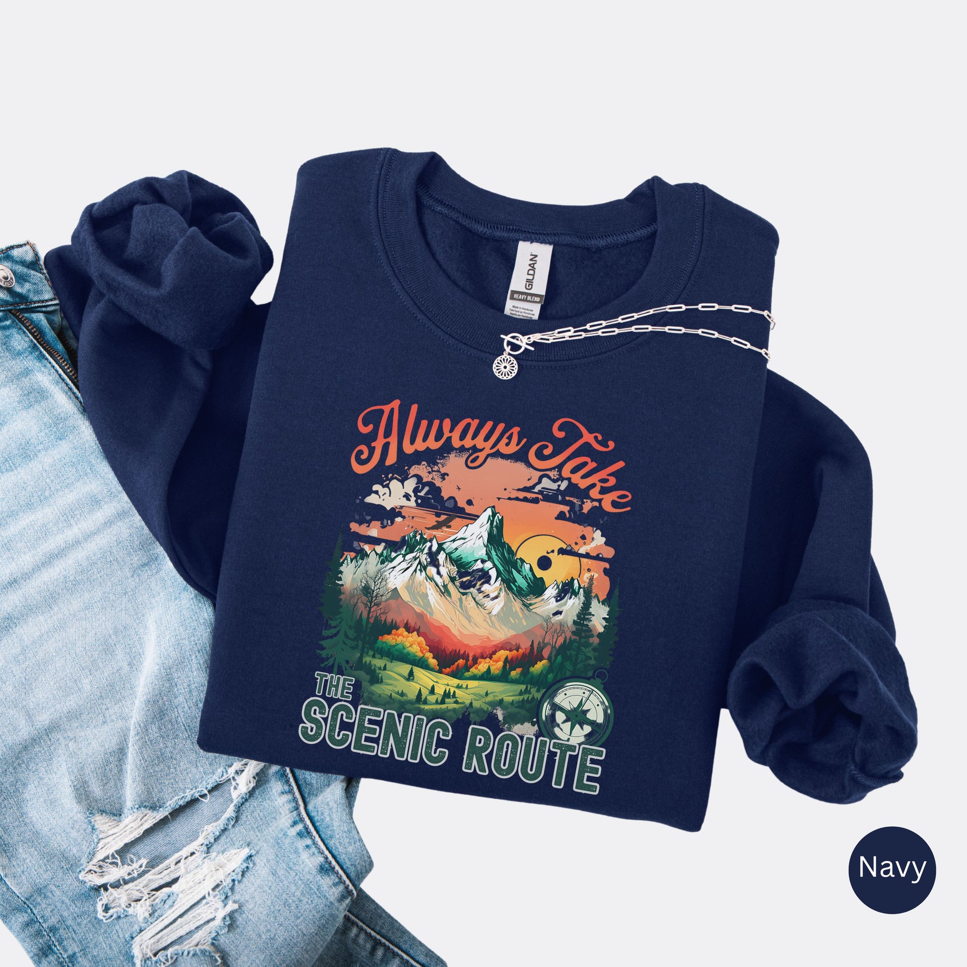 Crewneck sweatshirt in the color navy with the phrase “Always Take the Scenic Route” and a mountain-inspired graphic on the front.