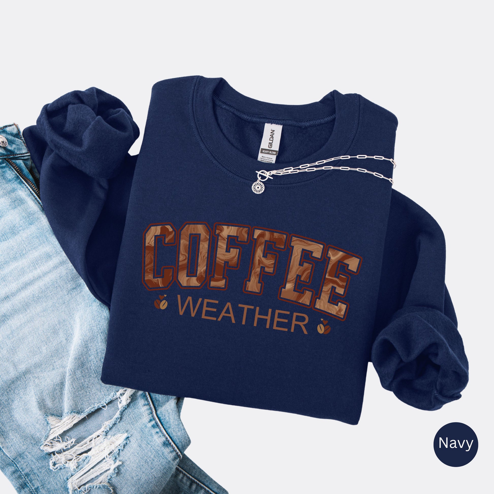 Coffee weather sweatshirt with marbled brown lettering and coffee bean icons on navy crewneck.