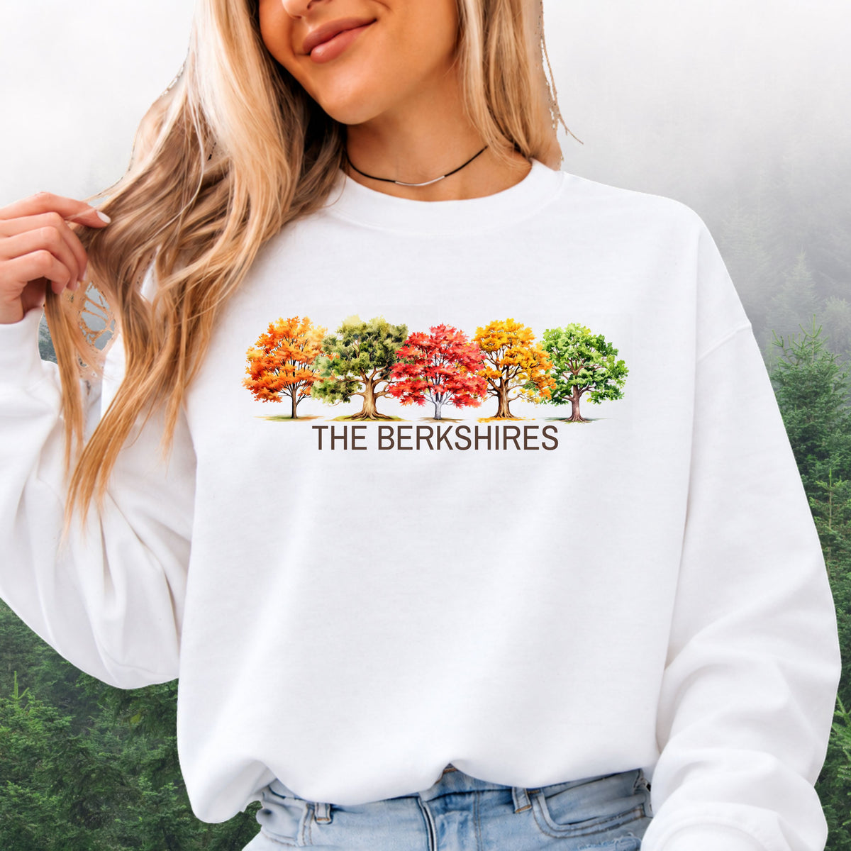 Person wearing white crewneck sweatshirt featuring colorful watercolor trees above the words The Berkshires.