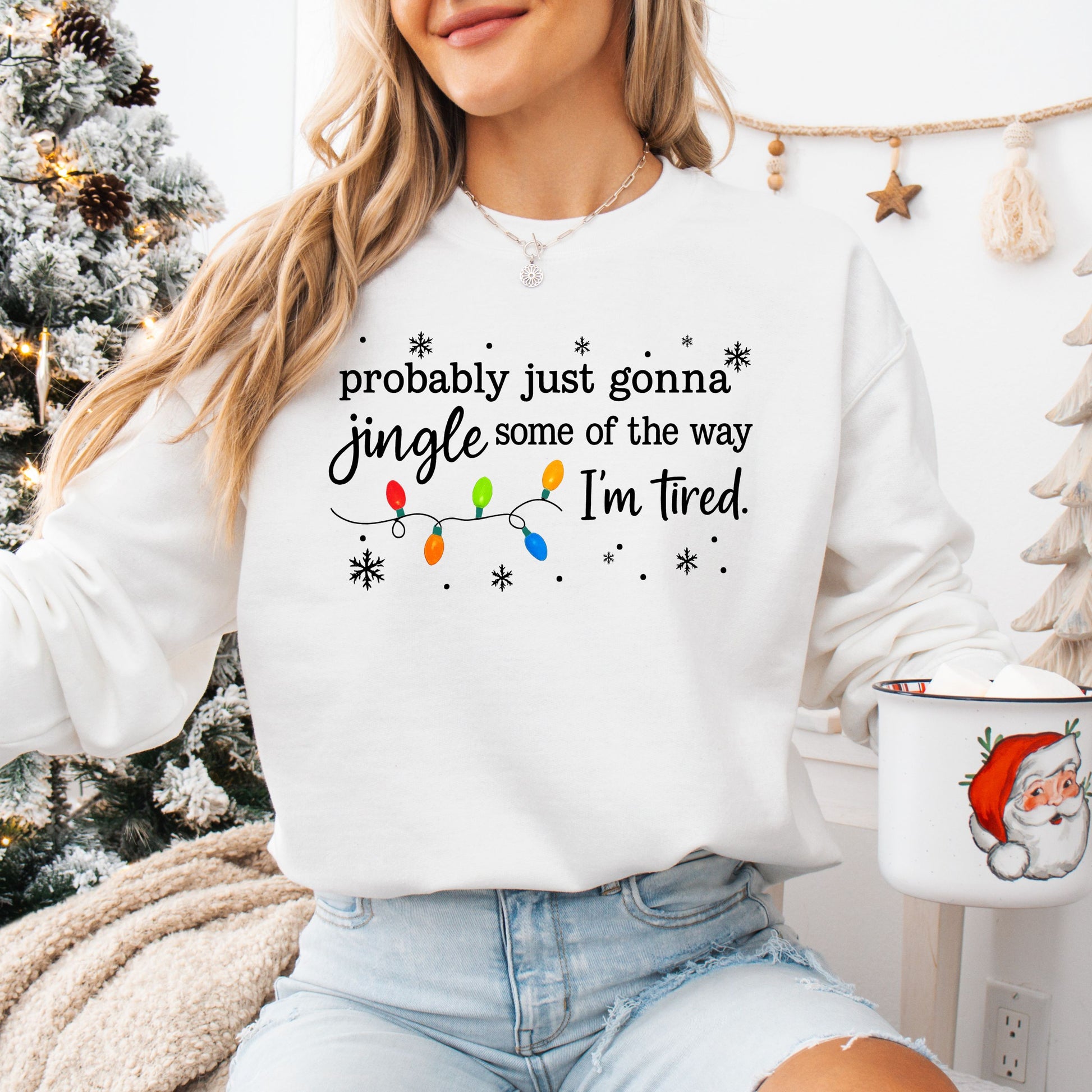 Person wearing a white sweatshirt with Christmas lights and the text "probably just gonna jingle some of the way I'm tired".