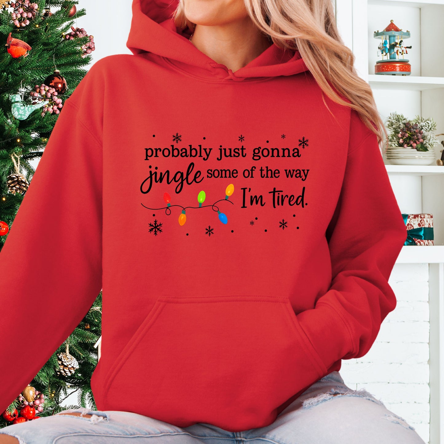 Person wearing red hoodie with Christmas lights and the text "probably just gonna jingle some of the way. I'm tired".