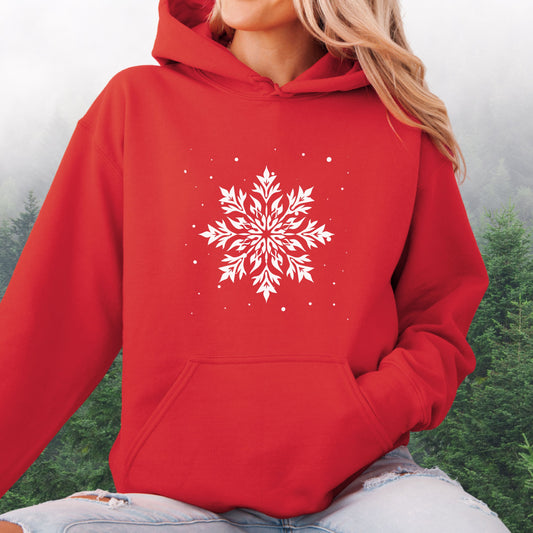 Person wearing snowflake design with falling snow on cozy unisex hoodie in the color red