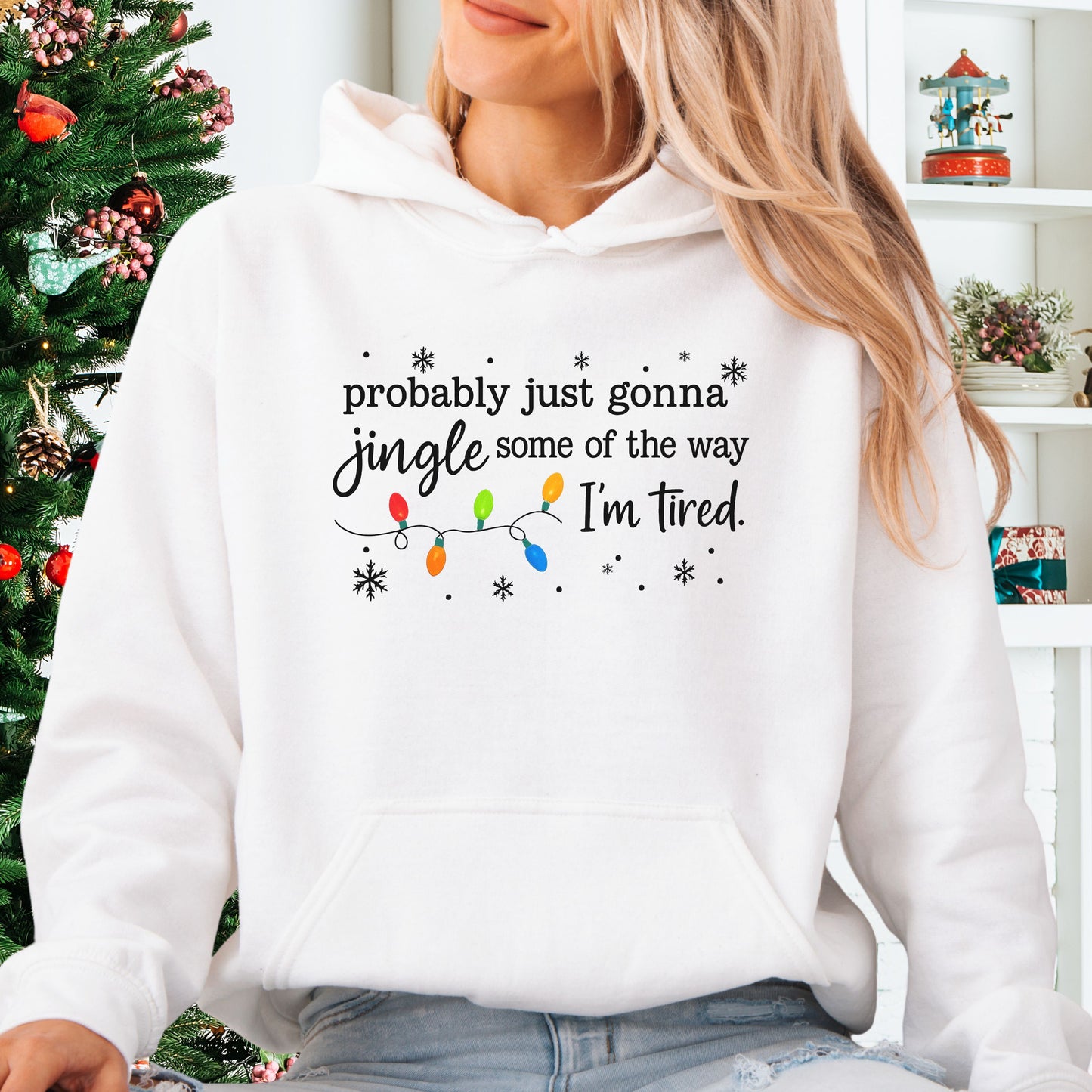 Person wearing white hoodie with Christmas lights and the text "probably just gonna jingle some of the way. I'm tired".