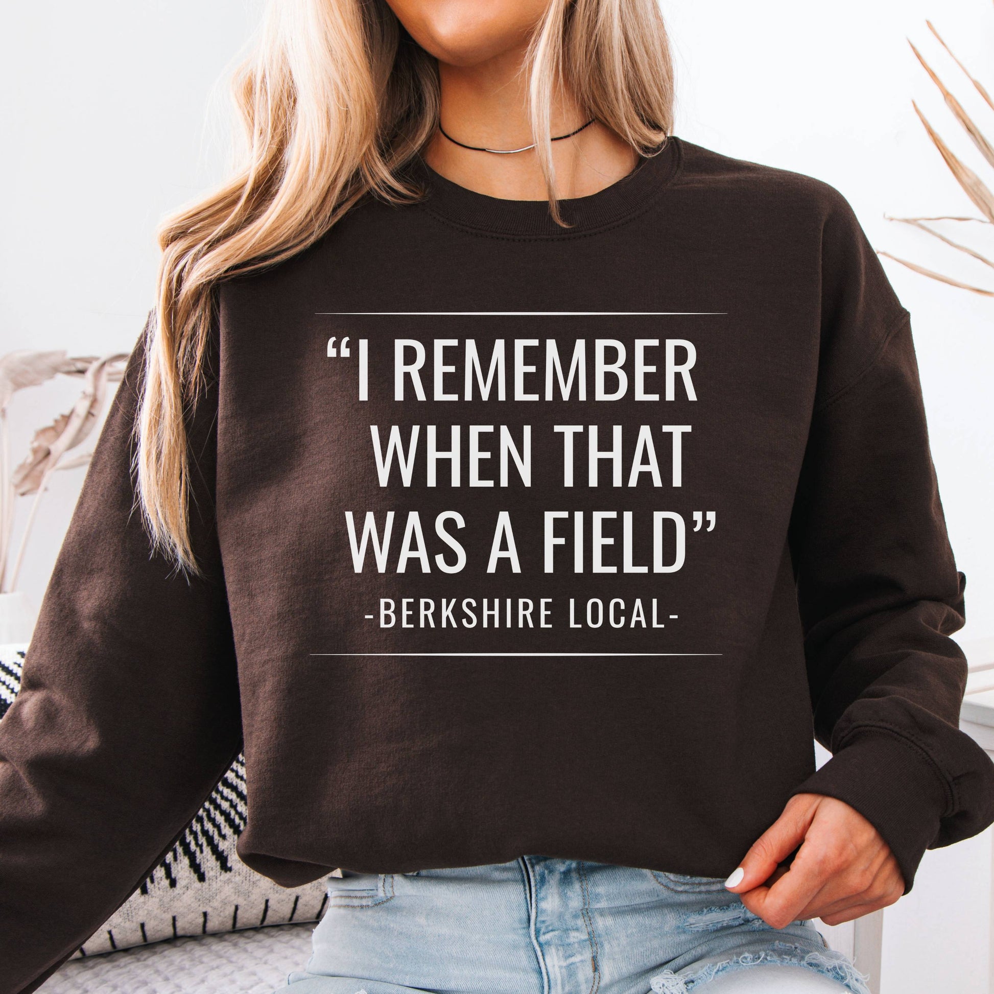 Person wearing sweatshirt with the quote "I remember when that was a field" -Berkshire Local-, in the color chocolate brown
